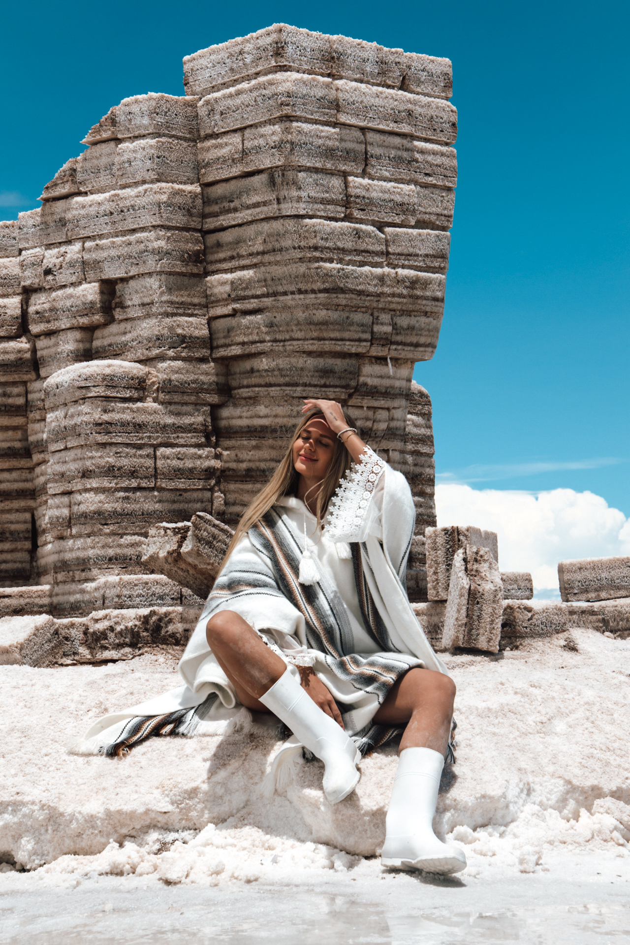 Woman sitting beside stacked salt blocks at Salar de Uyuni, Bolivia.