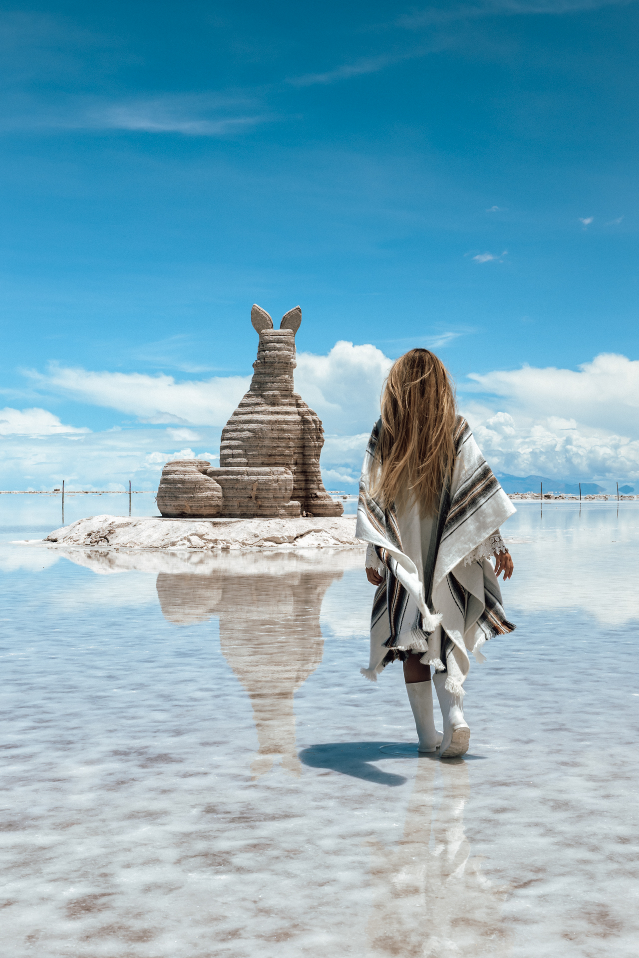 Walking toward the famous Dakar monument reflected on the endless mirror of Salar de Uyuni