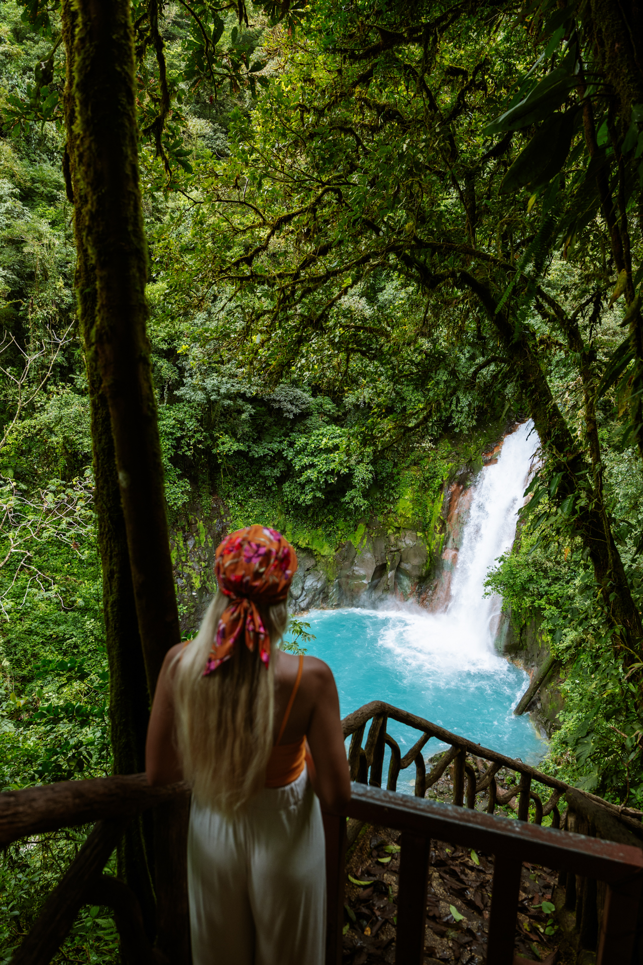 Woman looking at Río Celeste waterfall from a viewpoint in Tenorio Volcano National Park, Costa Rica