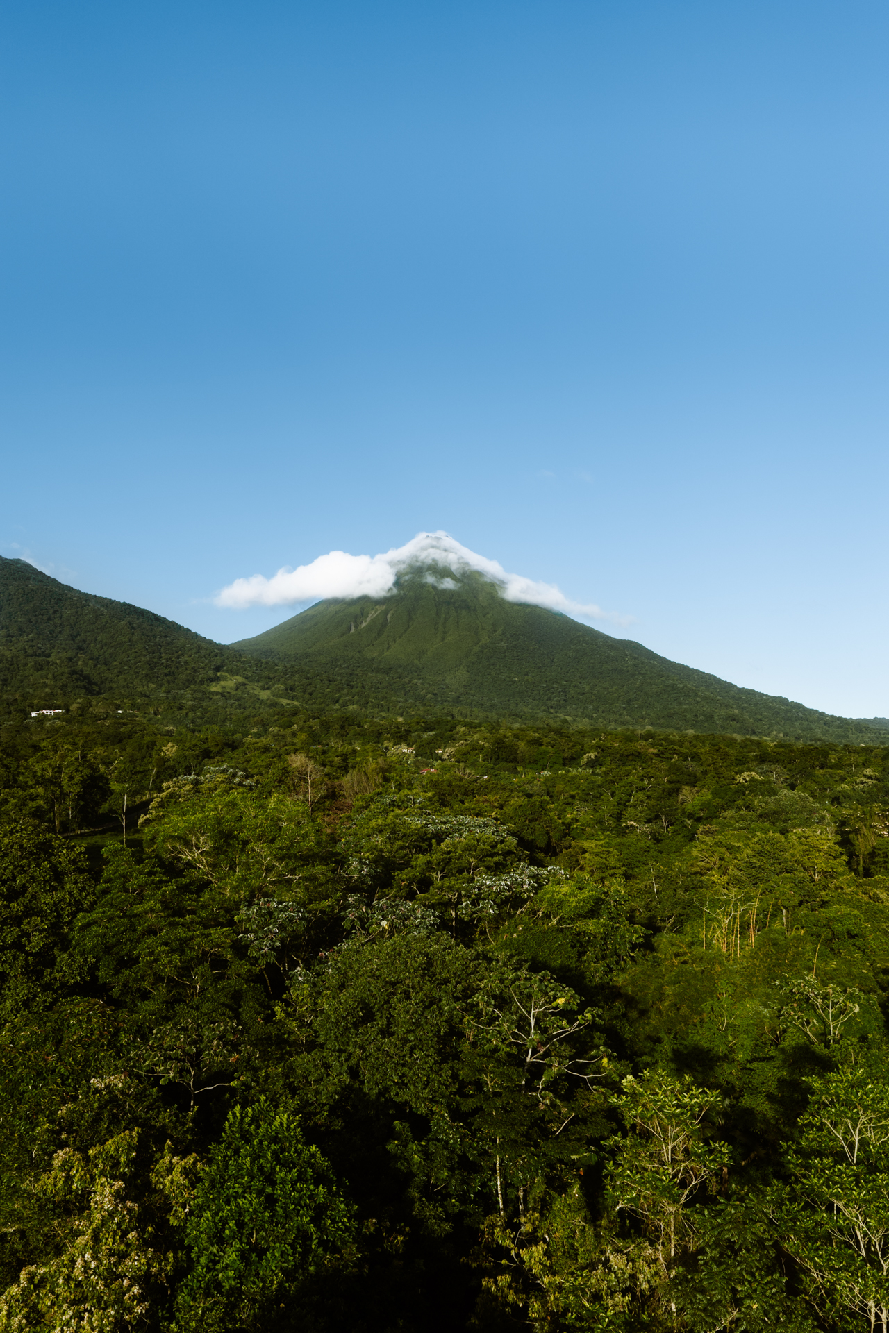 Arenal Volcano rising above lush rainforest in La Fortuna Costa Rica with clouds around the peak