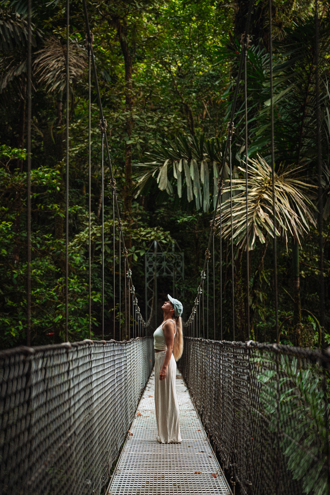Woman standing on a hanging bridge surrounded by rainforest in Mistico Arenal Hanging Bridges, La Fortuna