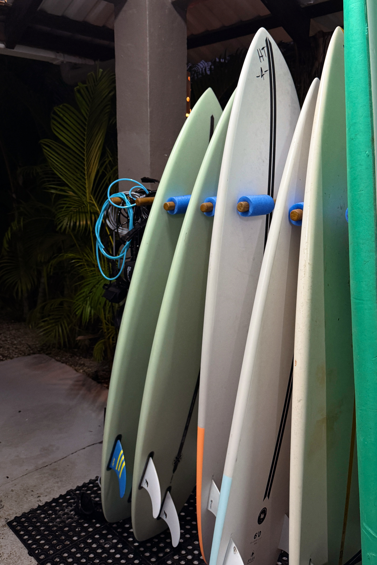 Surfboards lined up at a surf shop in Santa Teresa, Costa Rica surrounded by tropical plants