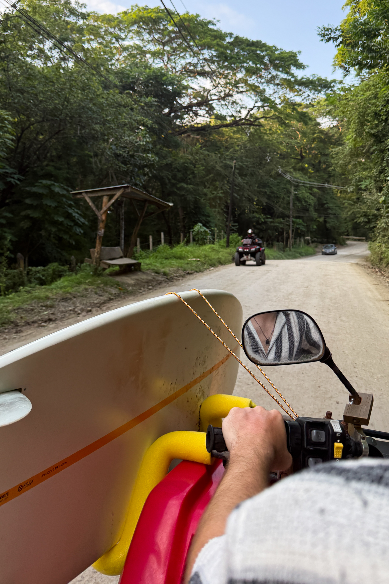 Riding an ATV with a surfboard along a jungle road in Santa Teresa, Costa Rica