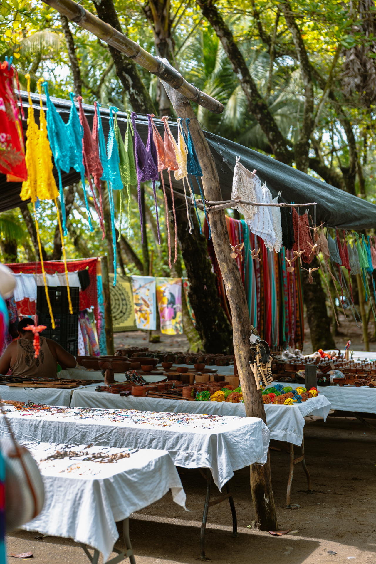 Colorful handicraft market stall in Costa Rica with textiles, jewelry and souvenirs.