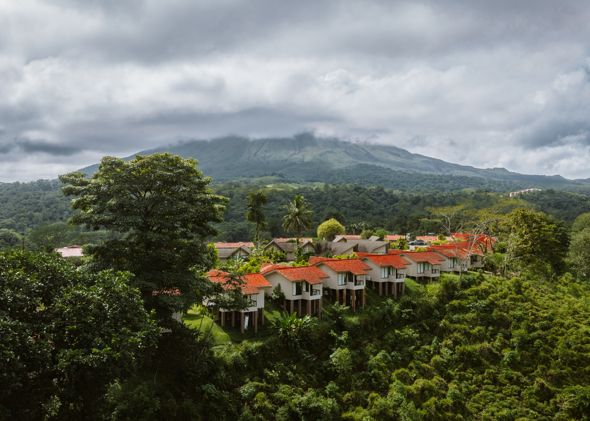 Arenal Volcano covered in clouds overlooking lush countryside and villas in La Fortuna, Costa Rica