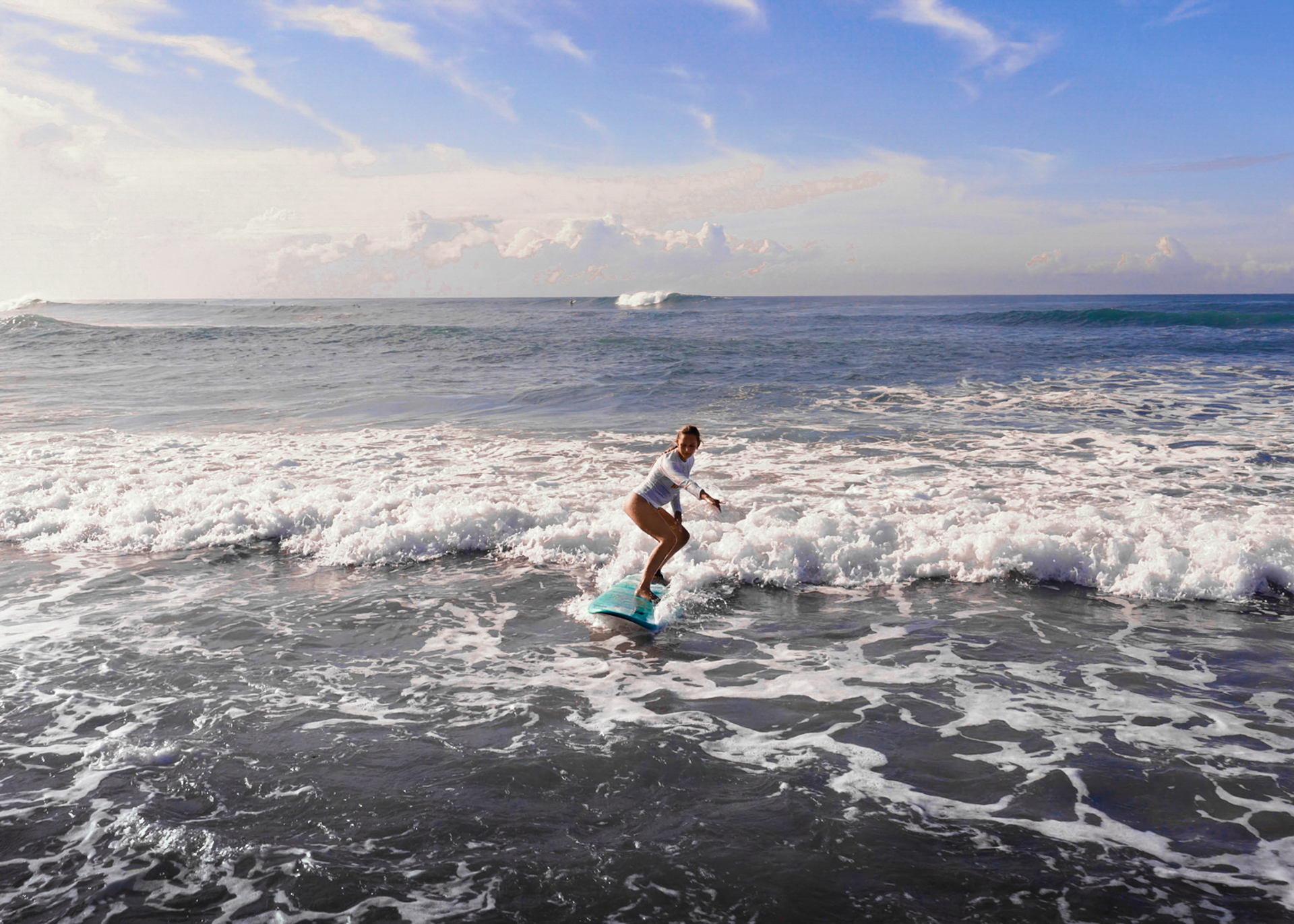 Surfer riding a wave in Santa Teresa, Costa Rica with blue ocean and gentle waves