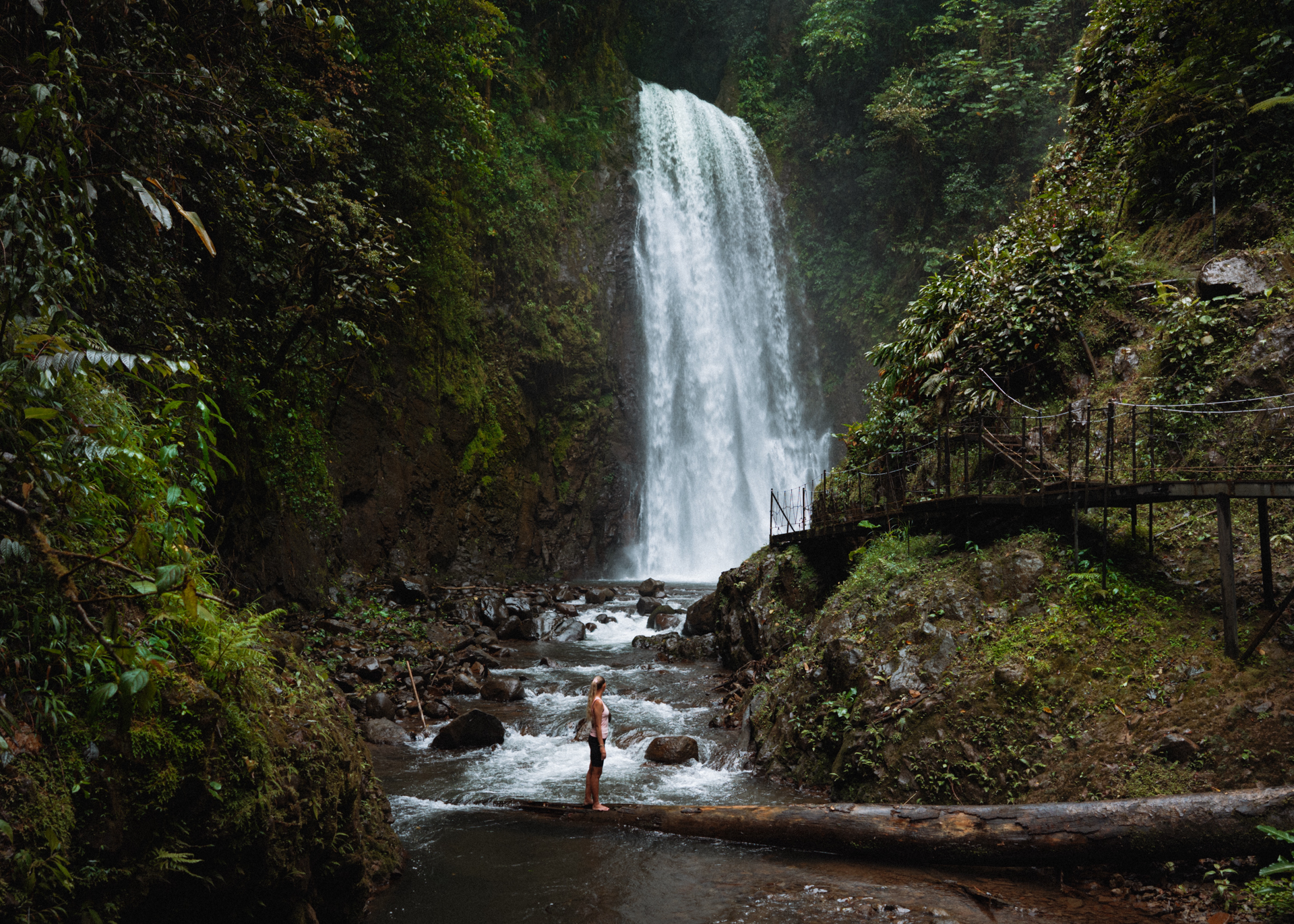 El Tigre Waterfall in Monteverde Costa Rica with person standing on log in river