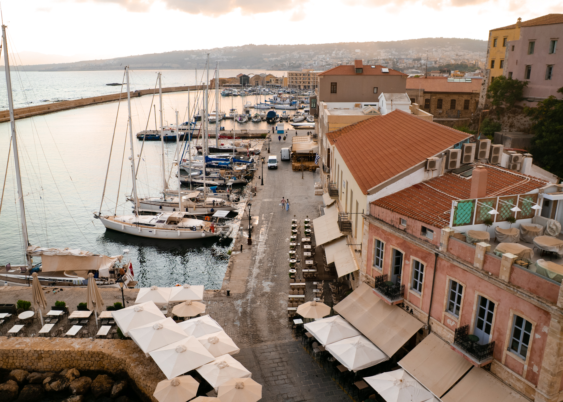 Sunset at Chania harbor with boats and waterfront cafes in Crete old town, Greece