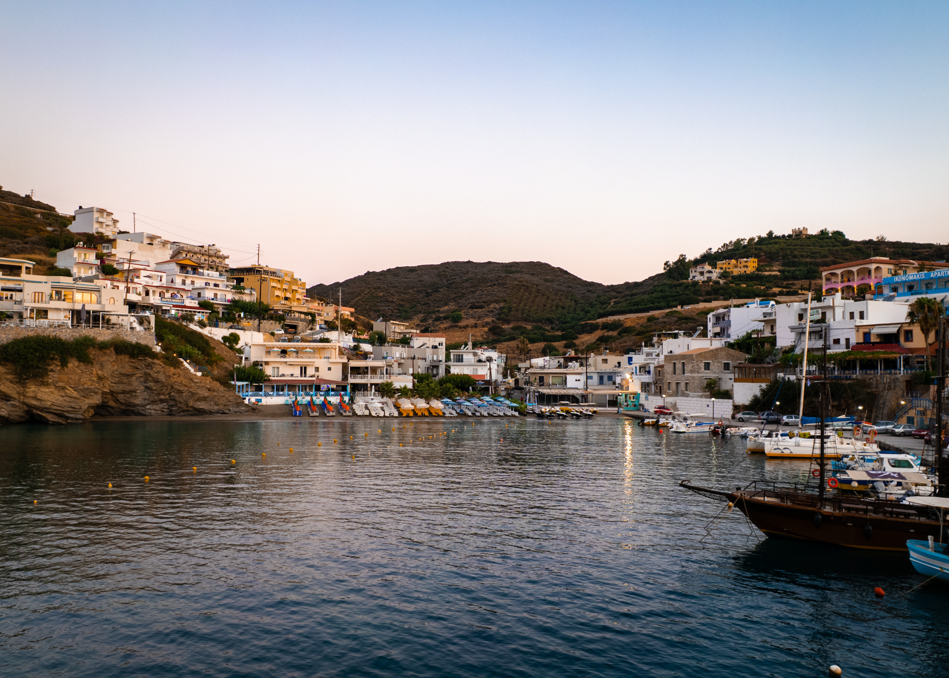 Rethymno coastal village harbor with boats and beach at sunset, Crete Greece