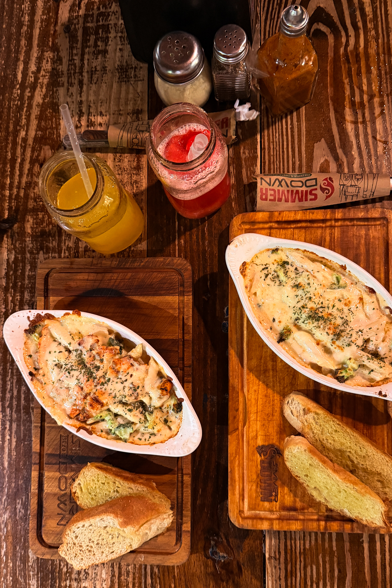 Baked pasta dishes and drinks served on wooden table at Simmer Down in Santa Ana