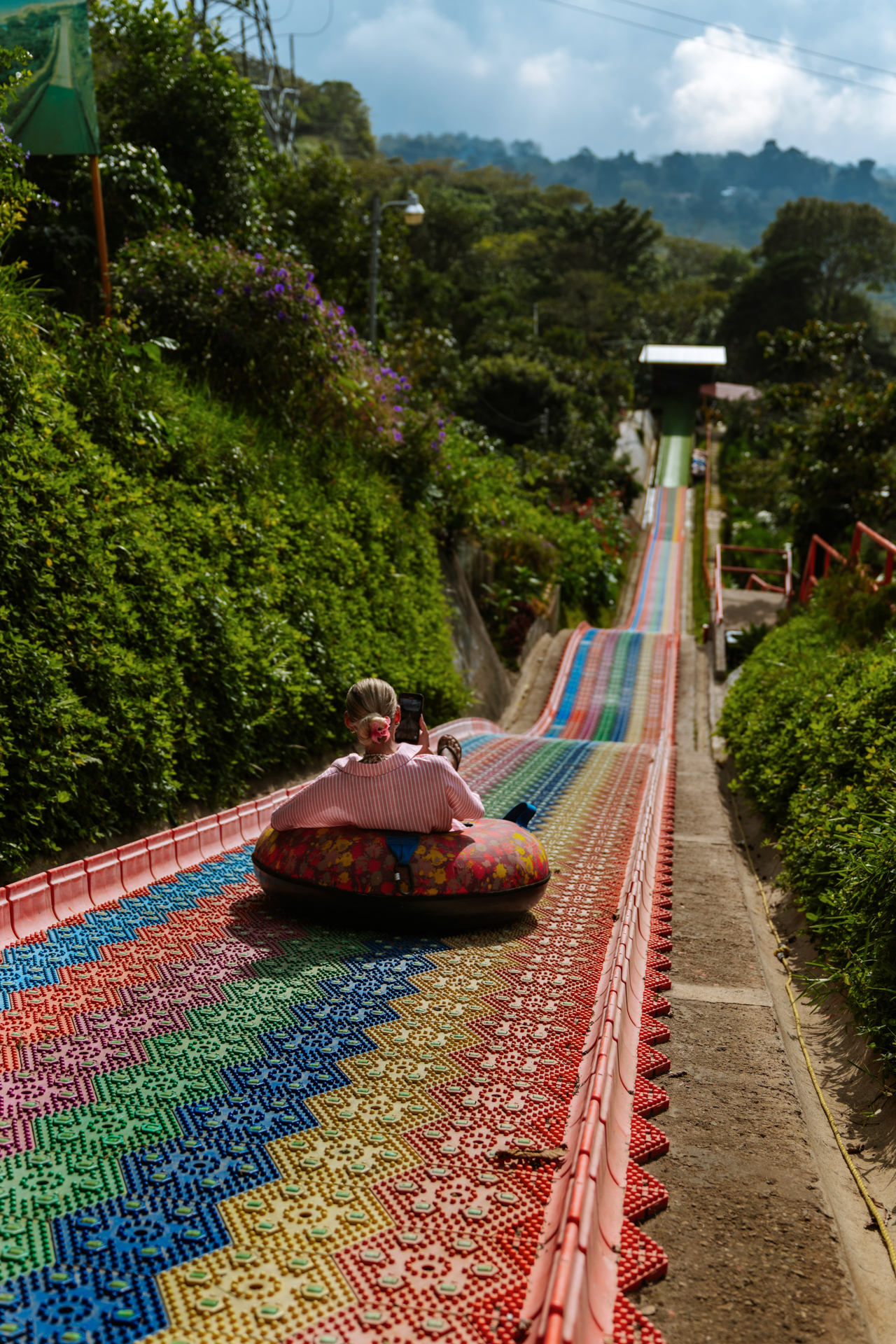Traveler riding the colorful rainbow slide at Café Albania in Apaneca on El Salvador’s Ruta de las Flores
