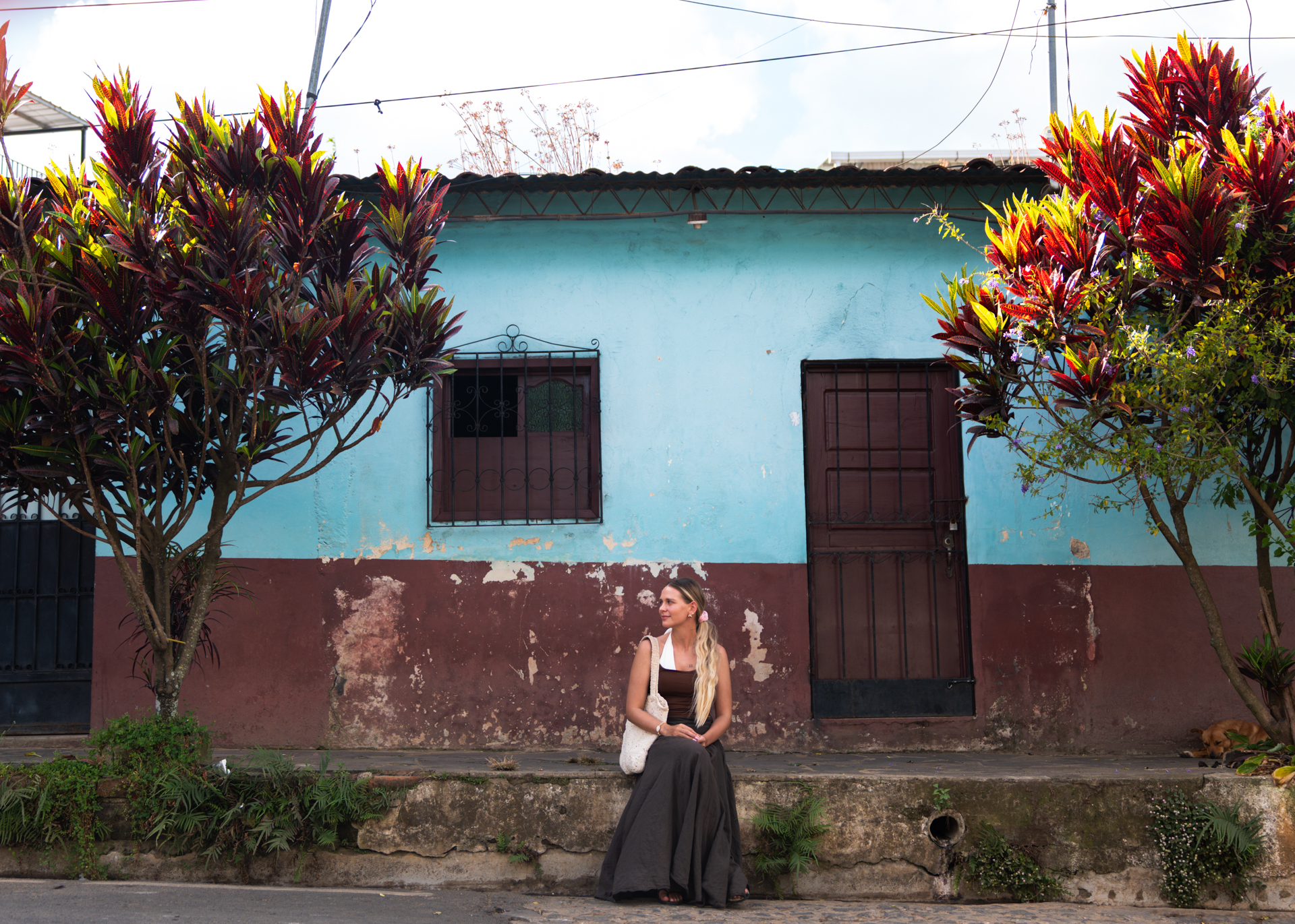 Traveler sitting in front of a colorful colonial house in Concepción de Ataco on El Salvador’s Ruta de las Flores