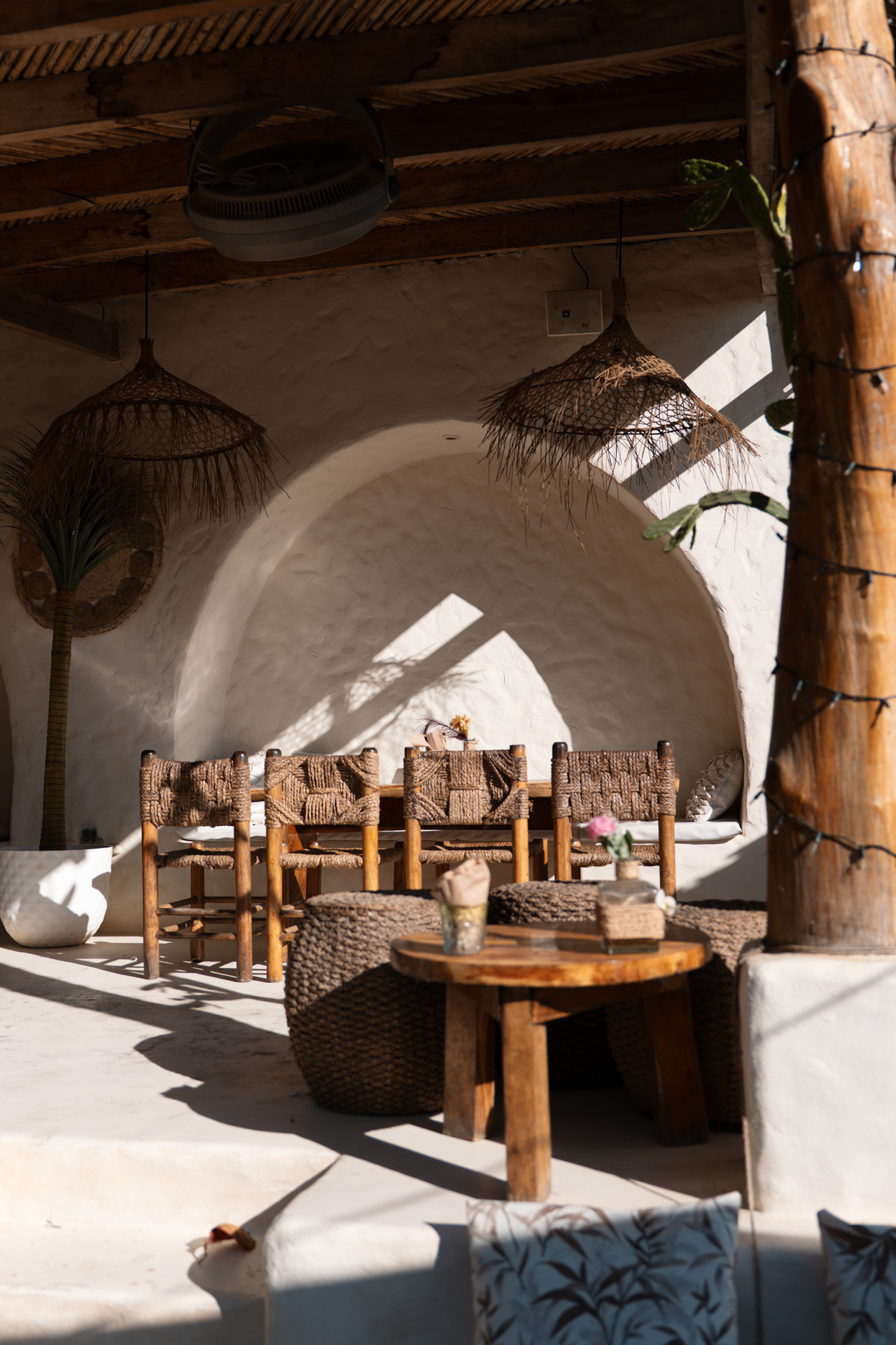 Cozy café interior in El Tunco with wooden chairs, woven lamps, and warm sunlight