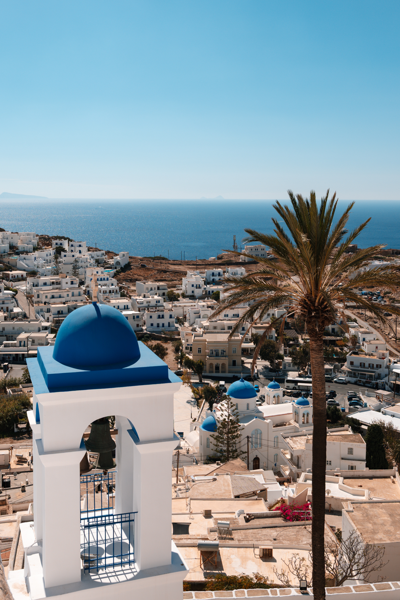 Ios island view with blue dome church, palm tree and sea in Cyclades Greece