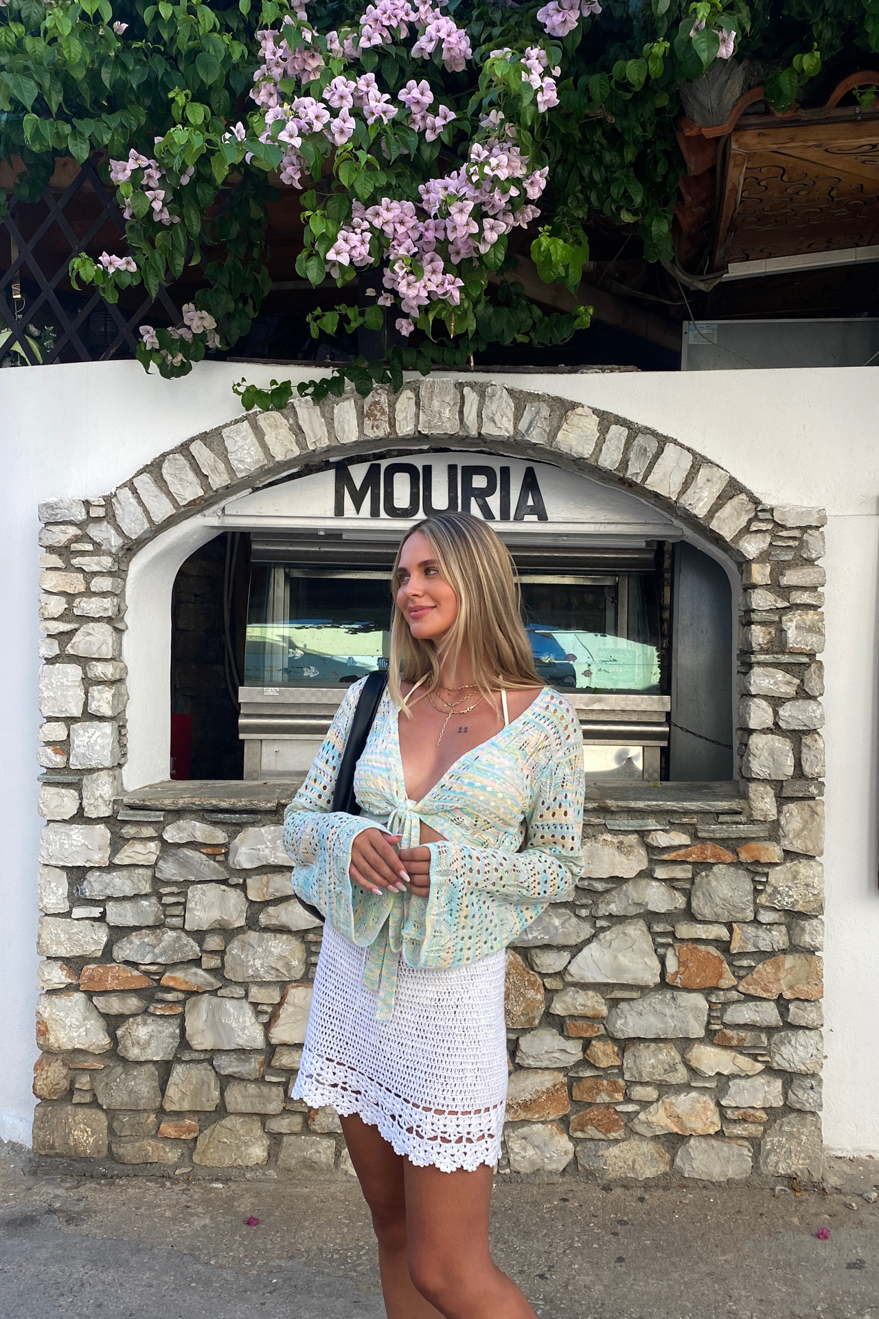Woman in Skiathos village with stone wall and flowers