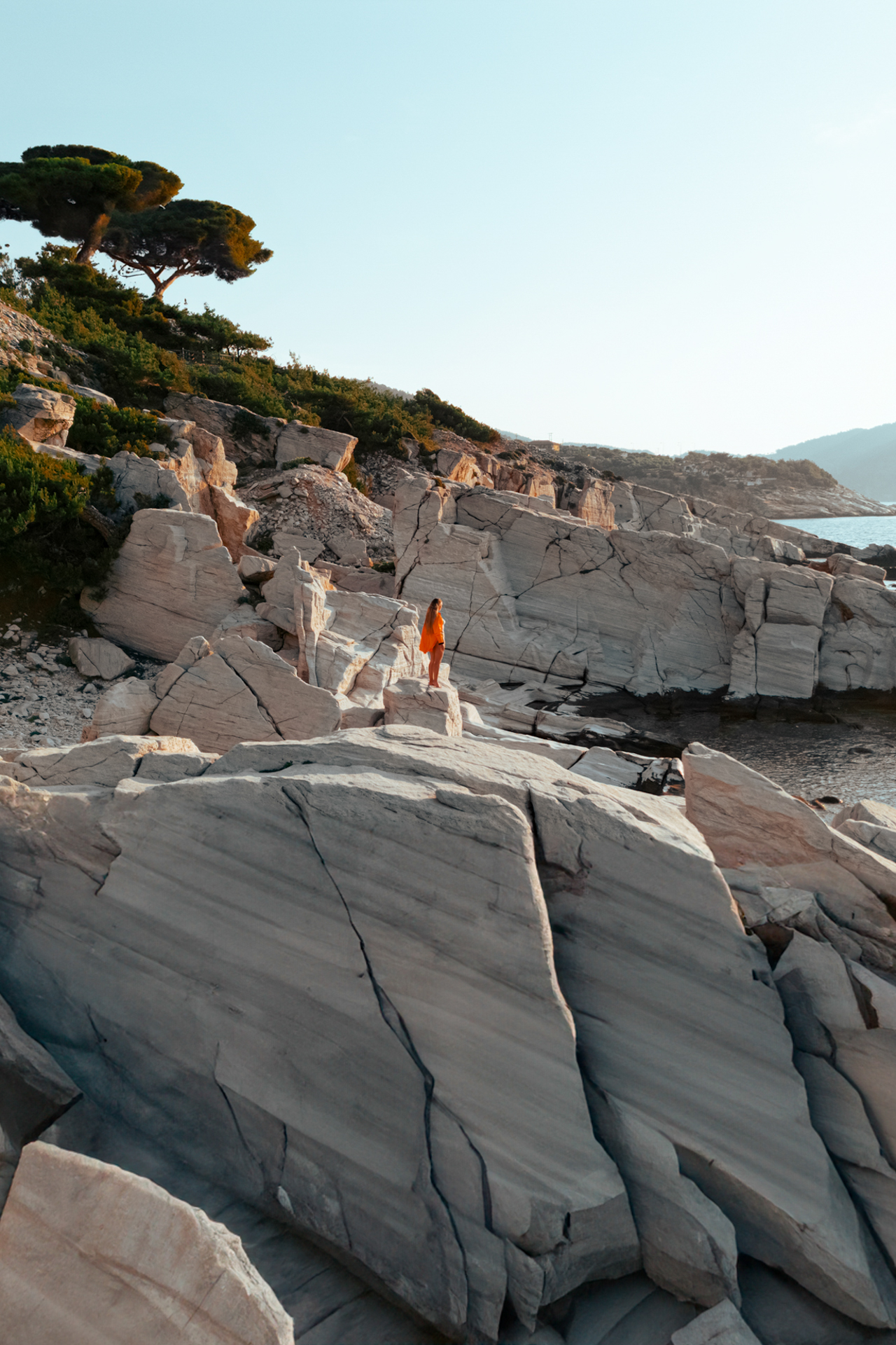 Woman standing on white marble rocks at Thassos coast, Greece seaside landscape