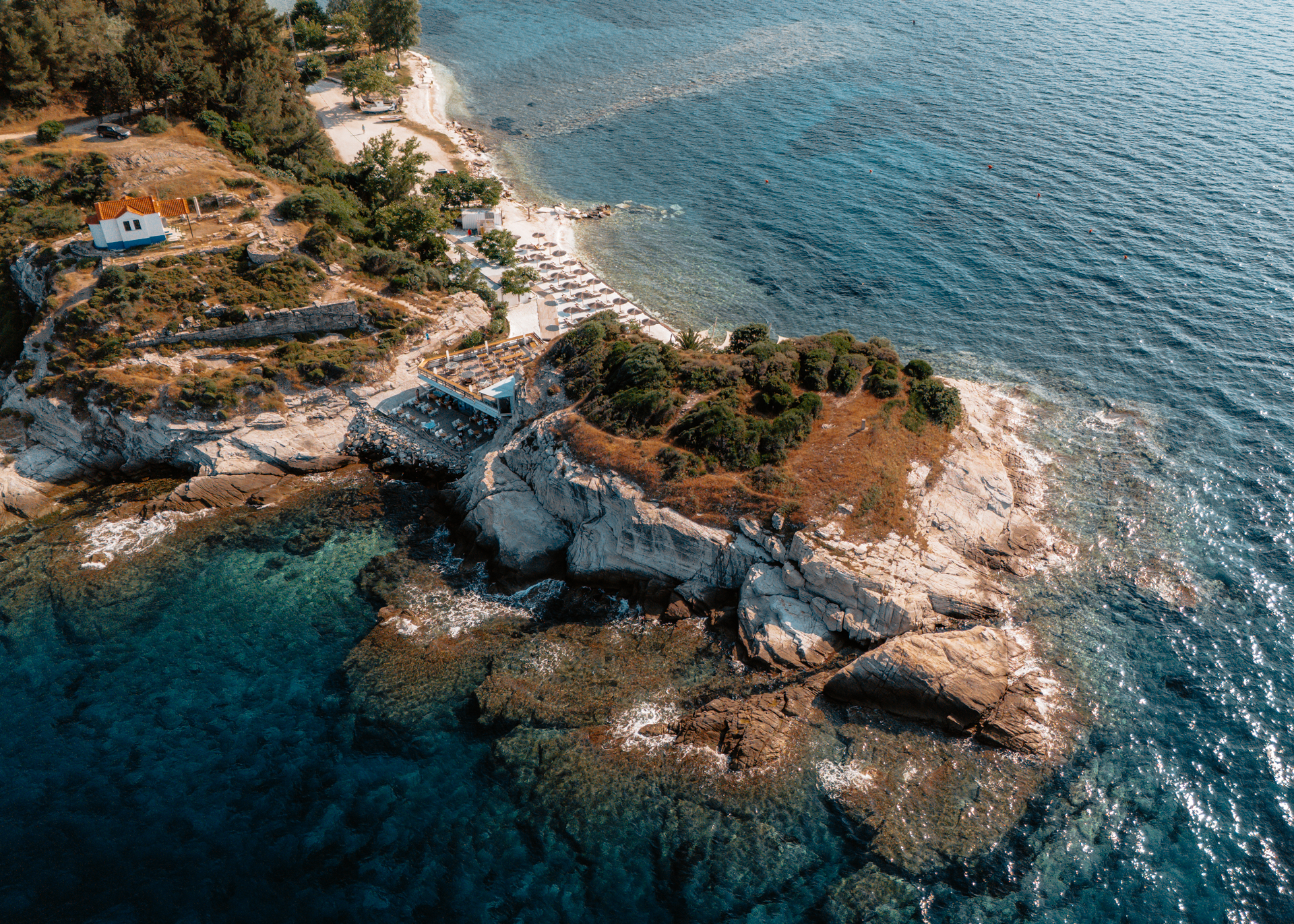 Aerial view of a beach and rocky coastline in Thassos, Greece with crystal clear turquoise water