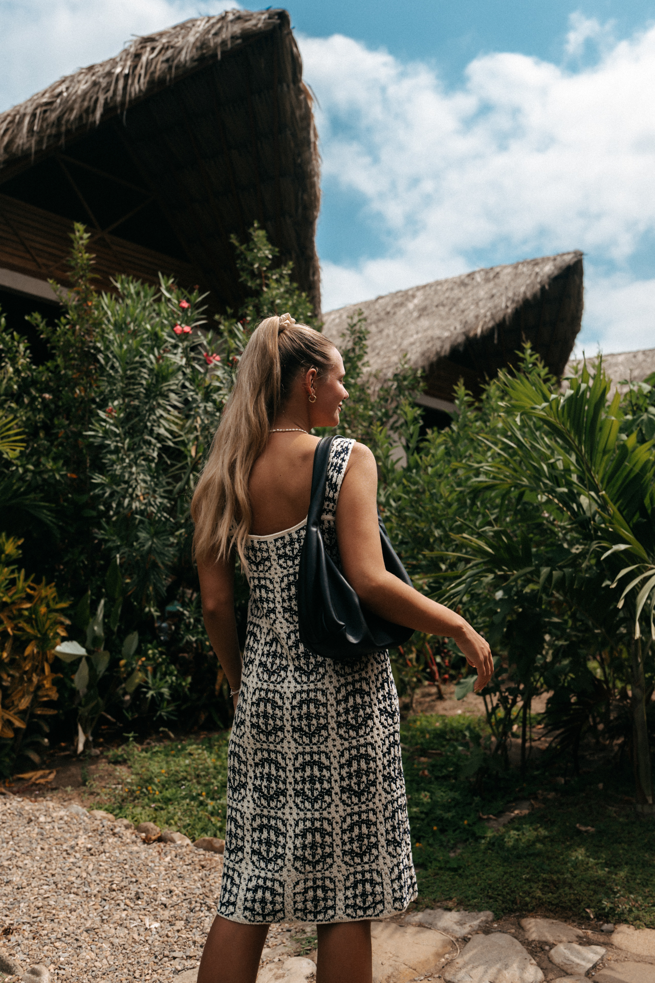 Woman walking through lush Palomino jungle with thatched roof huts