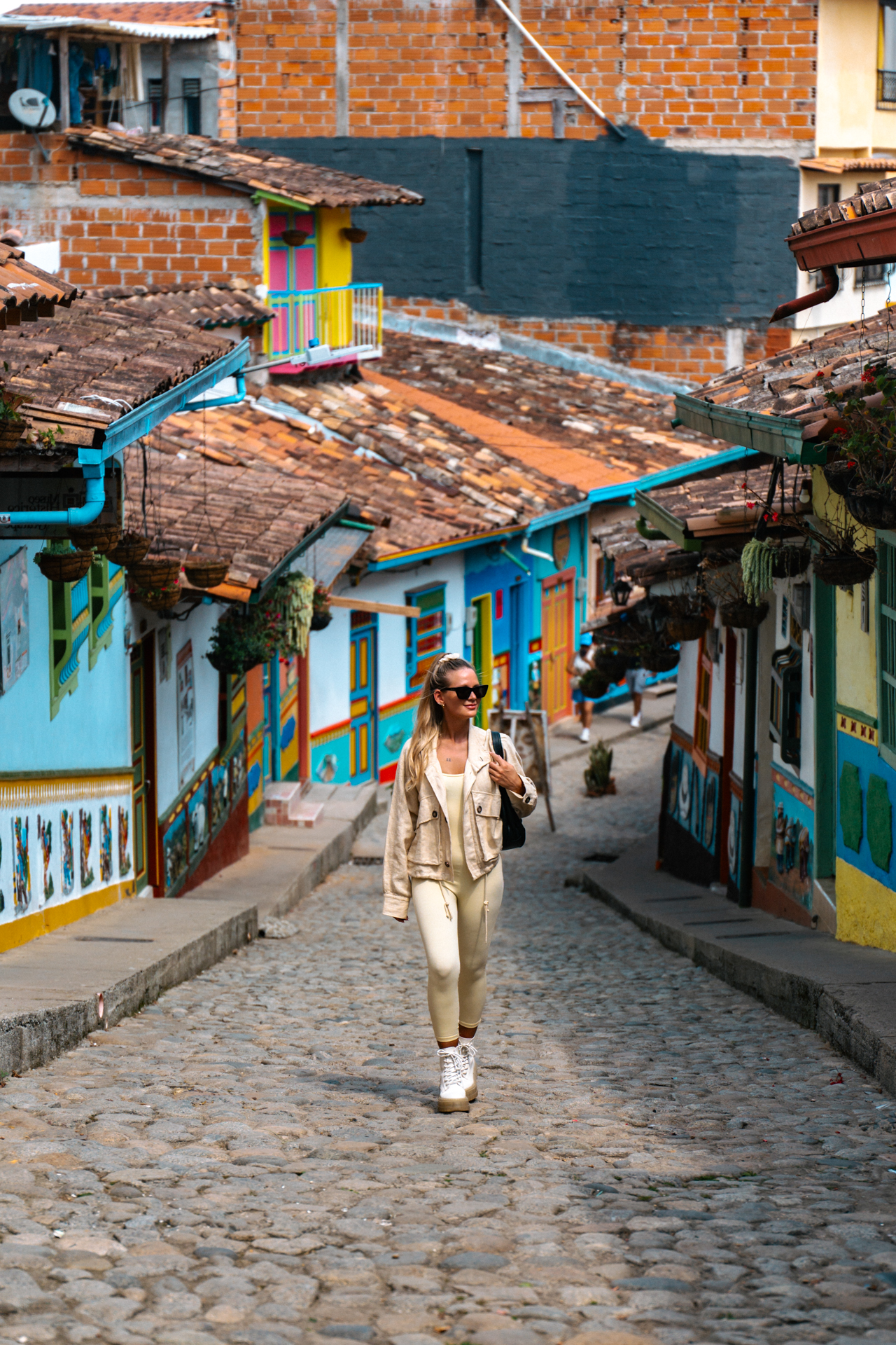 Woman walking Guatape colorful street with traditional houses and cobblestones