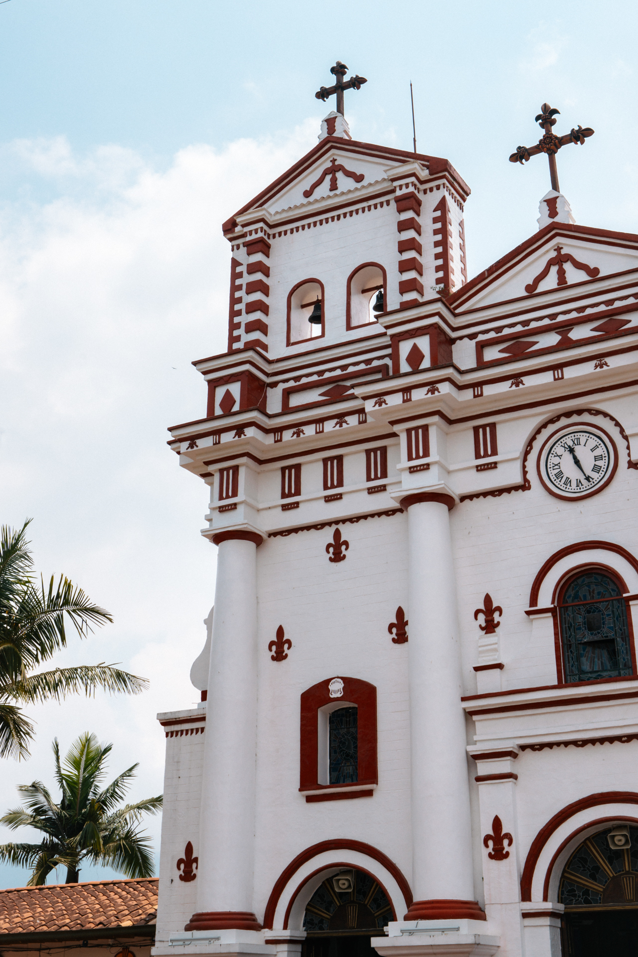 White and red Guatape church facade with colonial details and blue sky