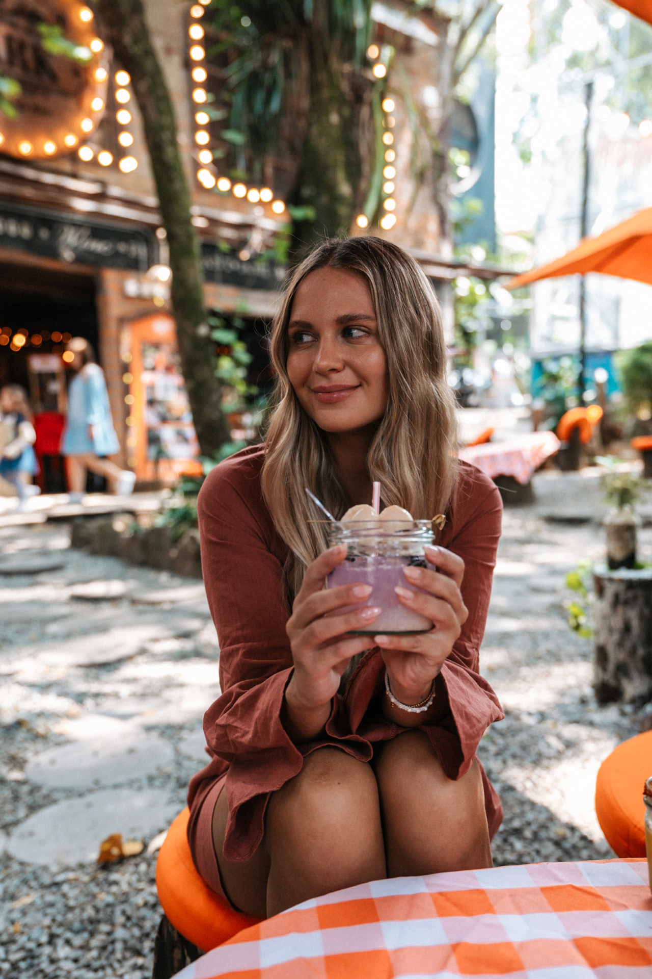 Woman enjoying dessert at cozy Medellin cafe with lights and tropical vibe