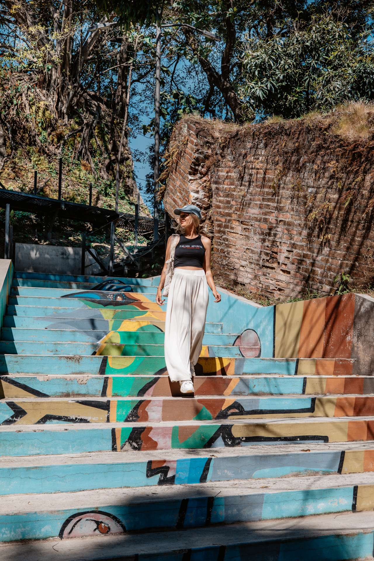 Woman walking down colorful painted stairs in Parque Cuscatlán, San Salvador