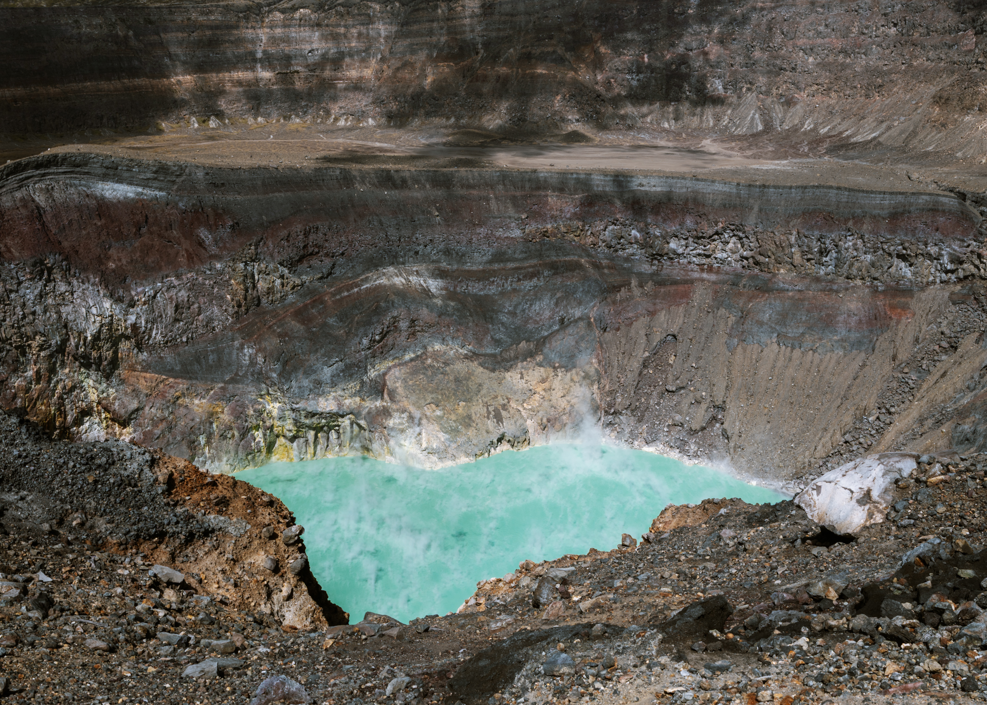 Aerial view of Santa Ana Volcano crater with a turquoise lake and surrounding rugged terrain
