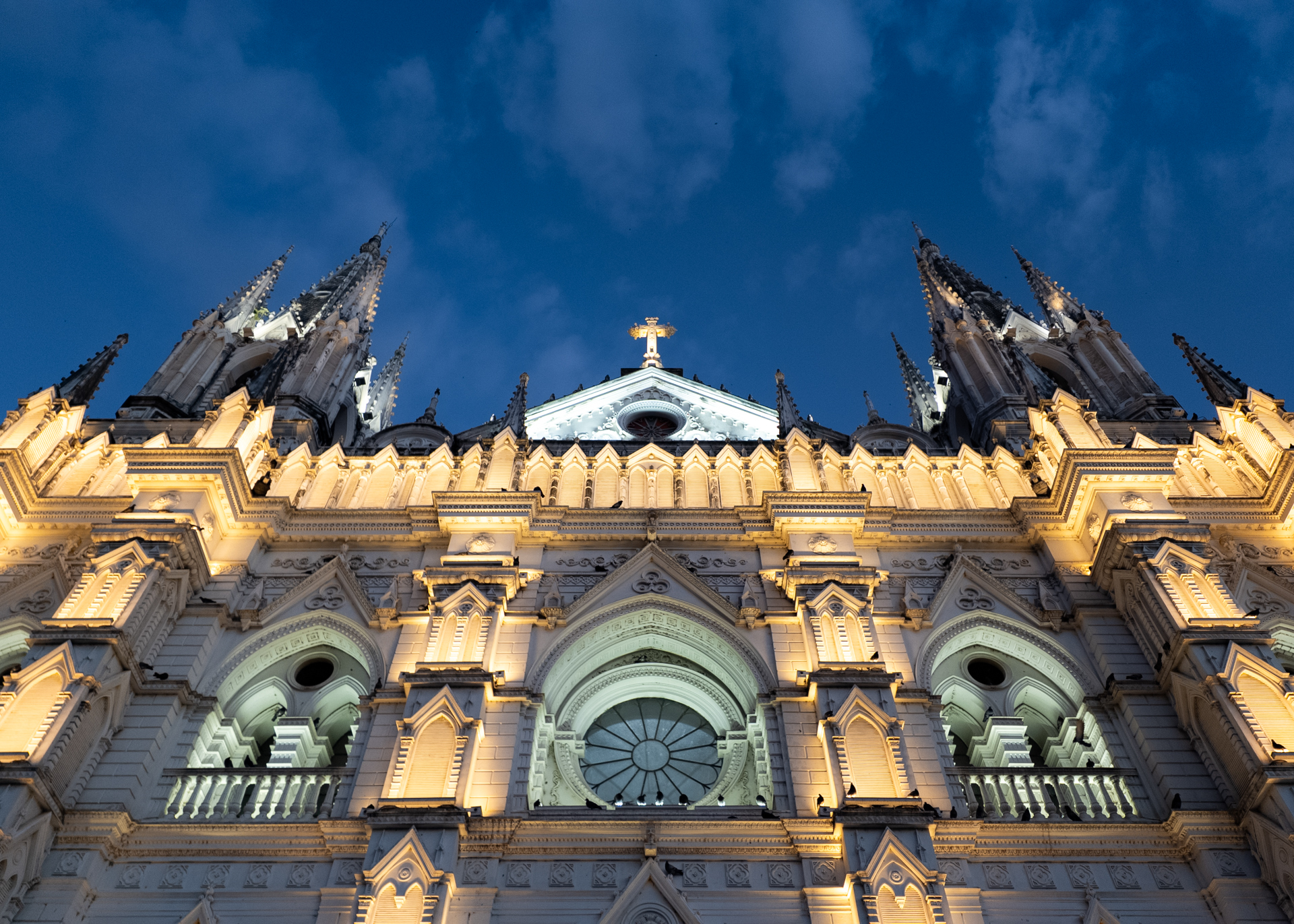 Illuminated Santa Ana Cathedral facade with gothic towers against a deep blue evening sky