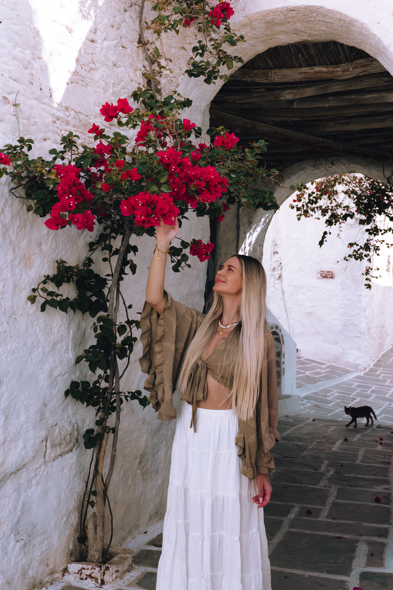 Woman under bougainvillea arch in Chora, Ios with whitewashed walls