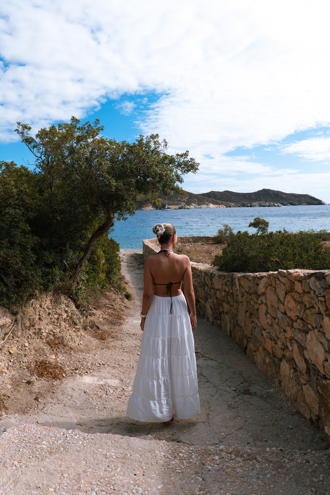 Woman walking coastal path near Tzamaria Beach, Ios with sea view