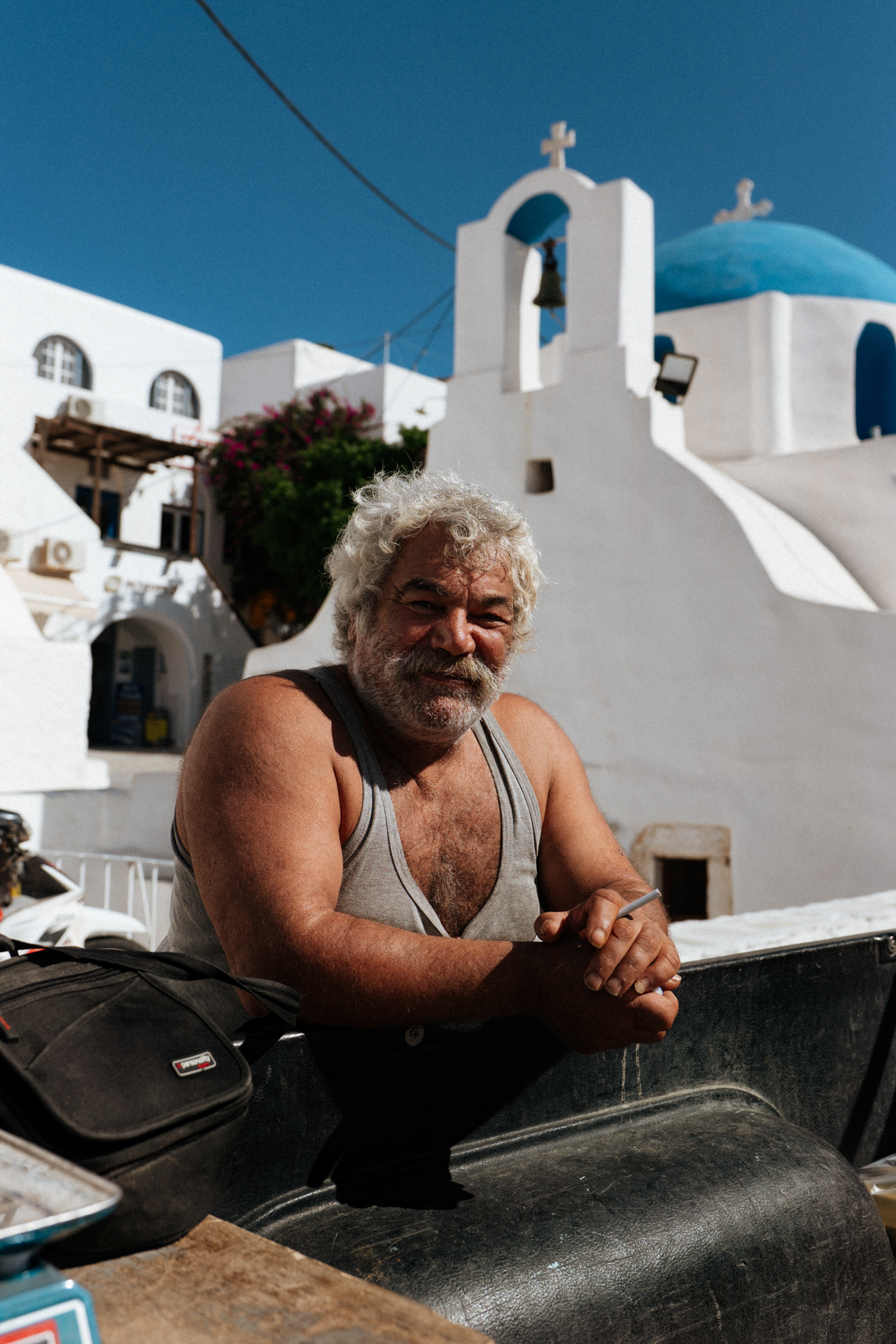 Local man in Chora, Ios with blue-domed church and white architecture