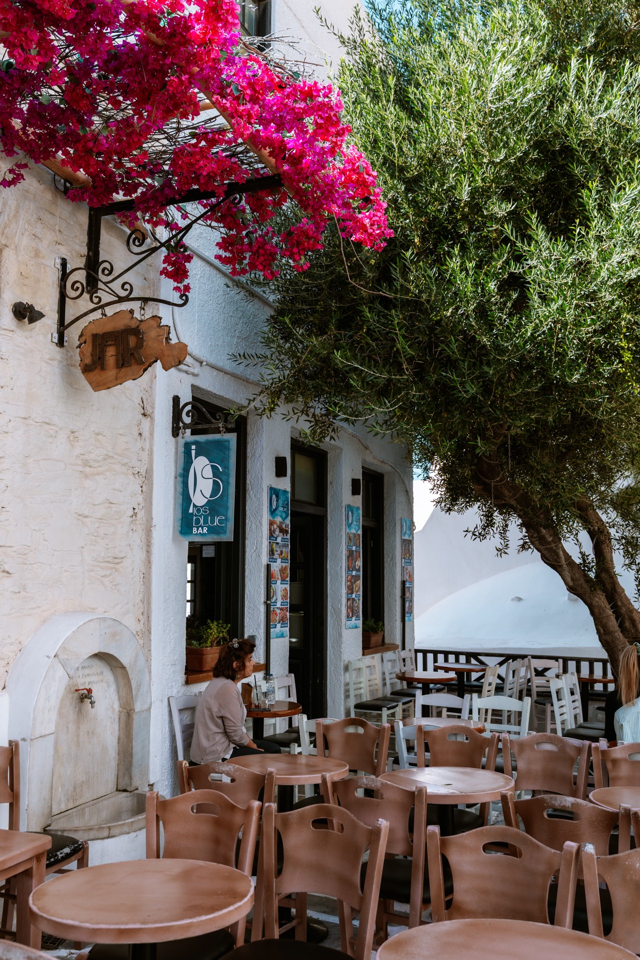 Outdoor café with bougainvillea and olive tree in Chora, Ios