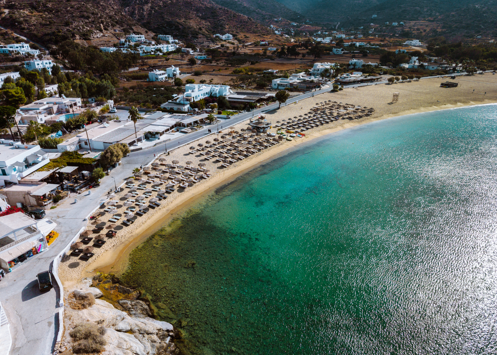 Aerial view of Mylopotas Beach, Ios with turquoise water and sunbeds along shore