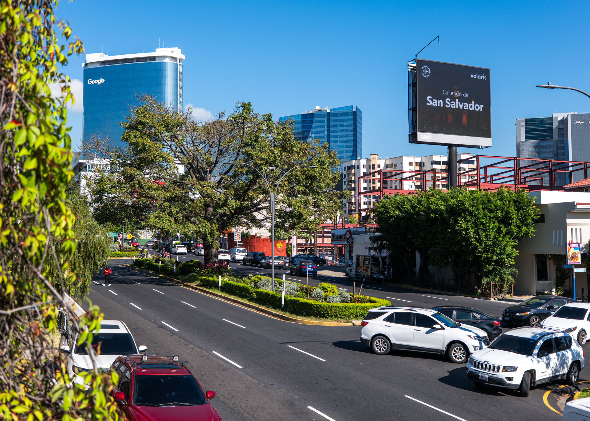 Street view of modern San Salvador in Zona Rosa with traffic, skyline, and Google building