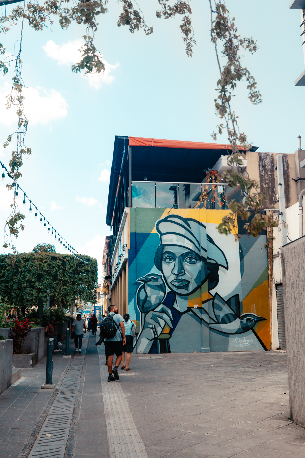 Street art mural of woman with birds on building in San Salvador