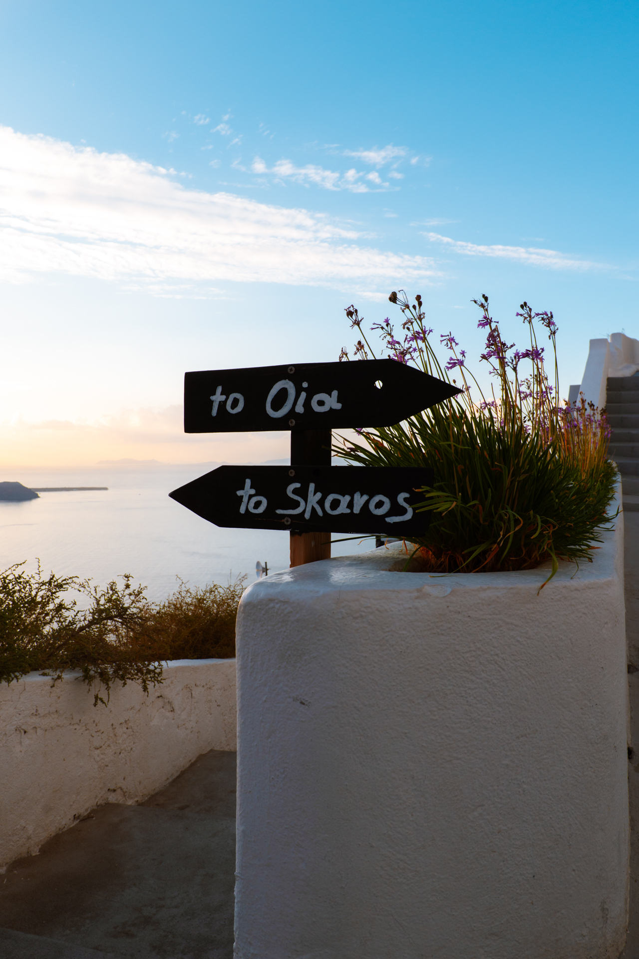 ignpost to Oia and Skaros Rock overlooking Santorini caldera at sunset