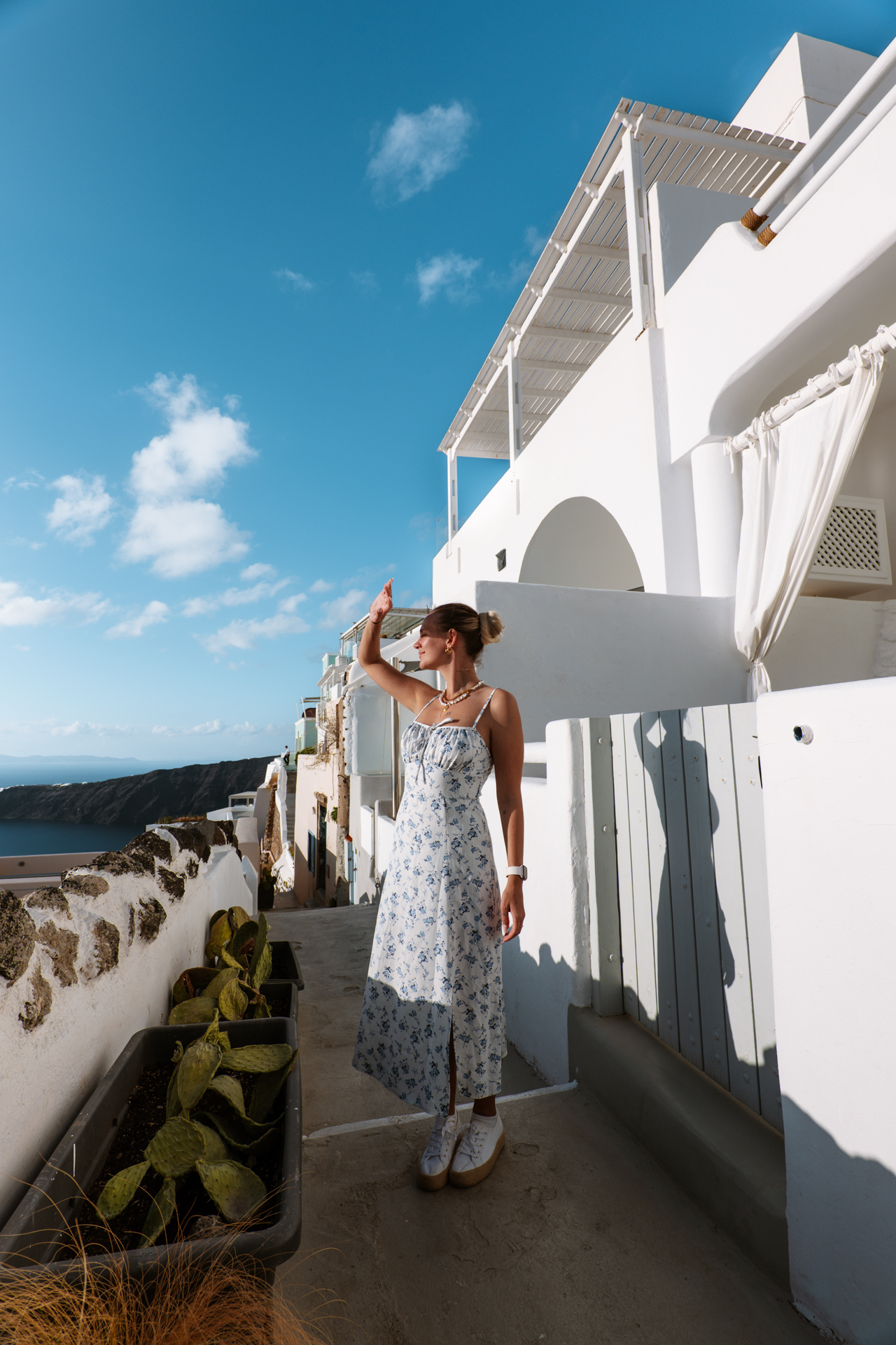 Woman in Imerovigli Santorini with white houses and caldera view under blue sky