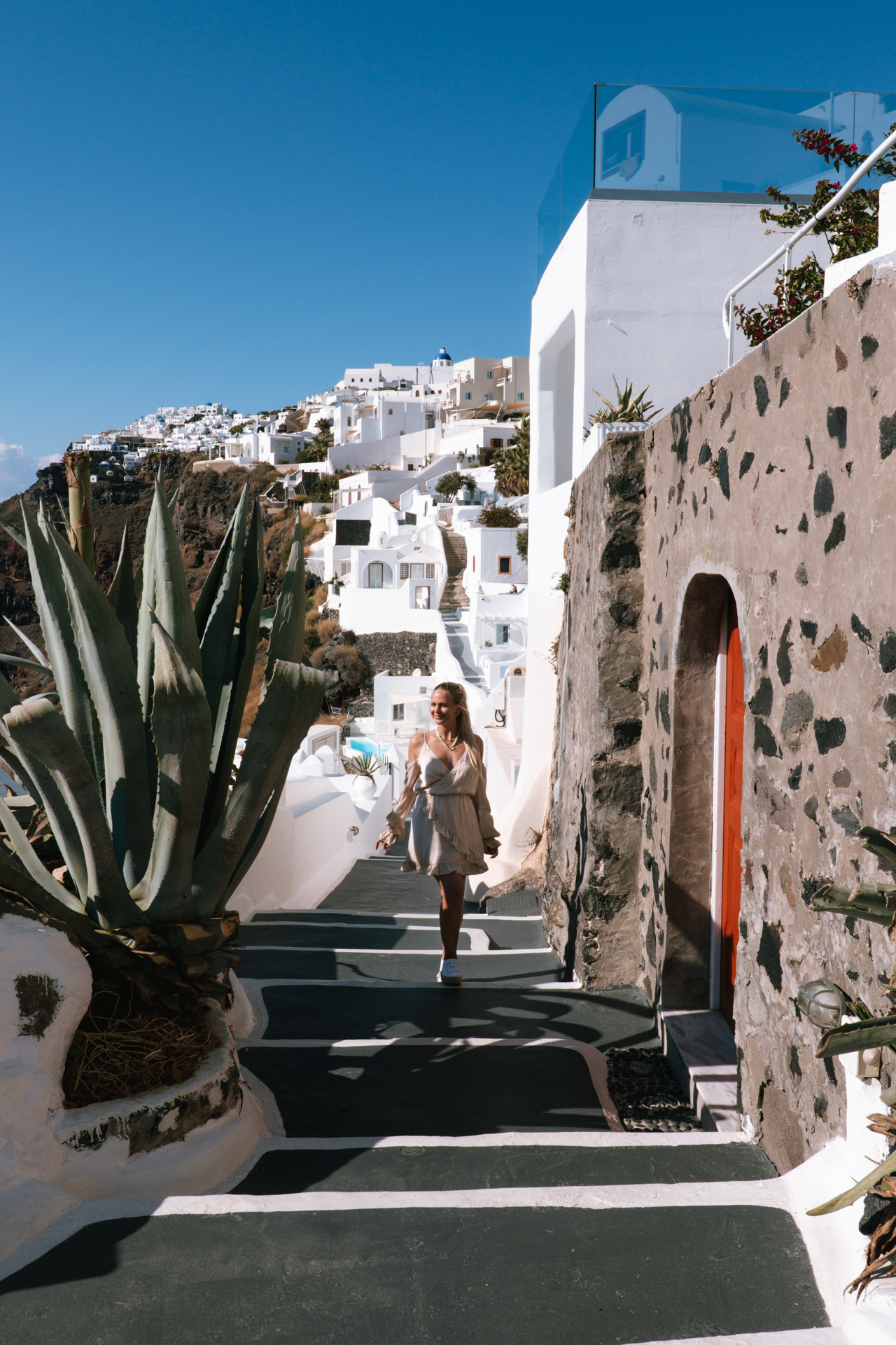 Woman walking in Oia Santorini with white houses and caldera sea view