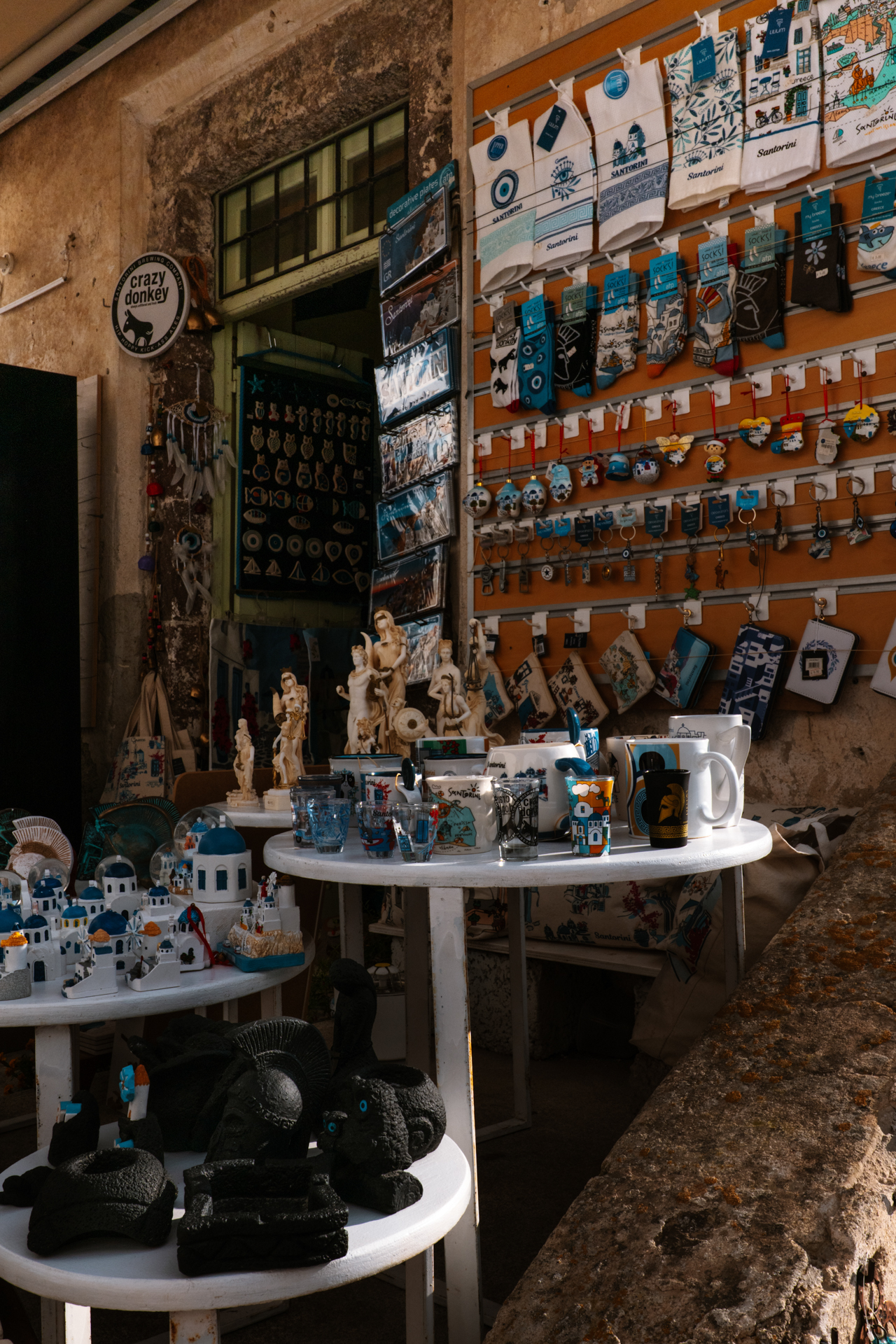 Souvenir shop in Pyrgos displaying handmade ceramics, magnets, and local crafts on tables in Santorini.