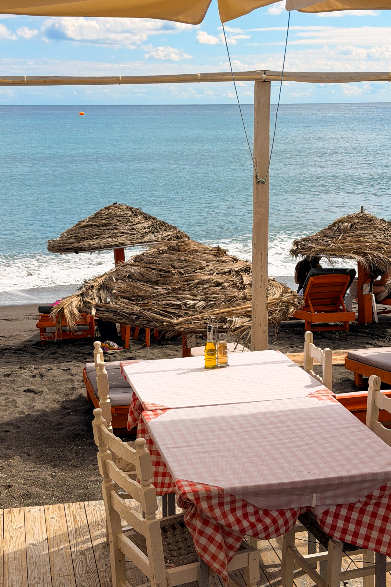 Perissa Beach Santorini restaurant terrace with sea view, umbrellas and black sand