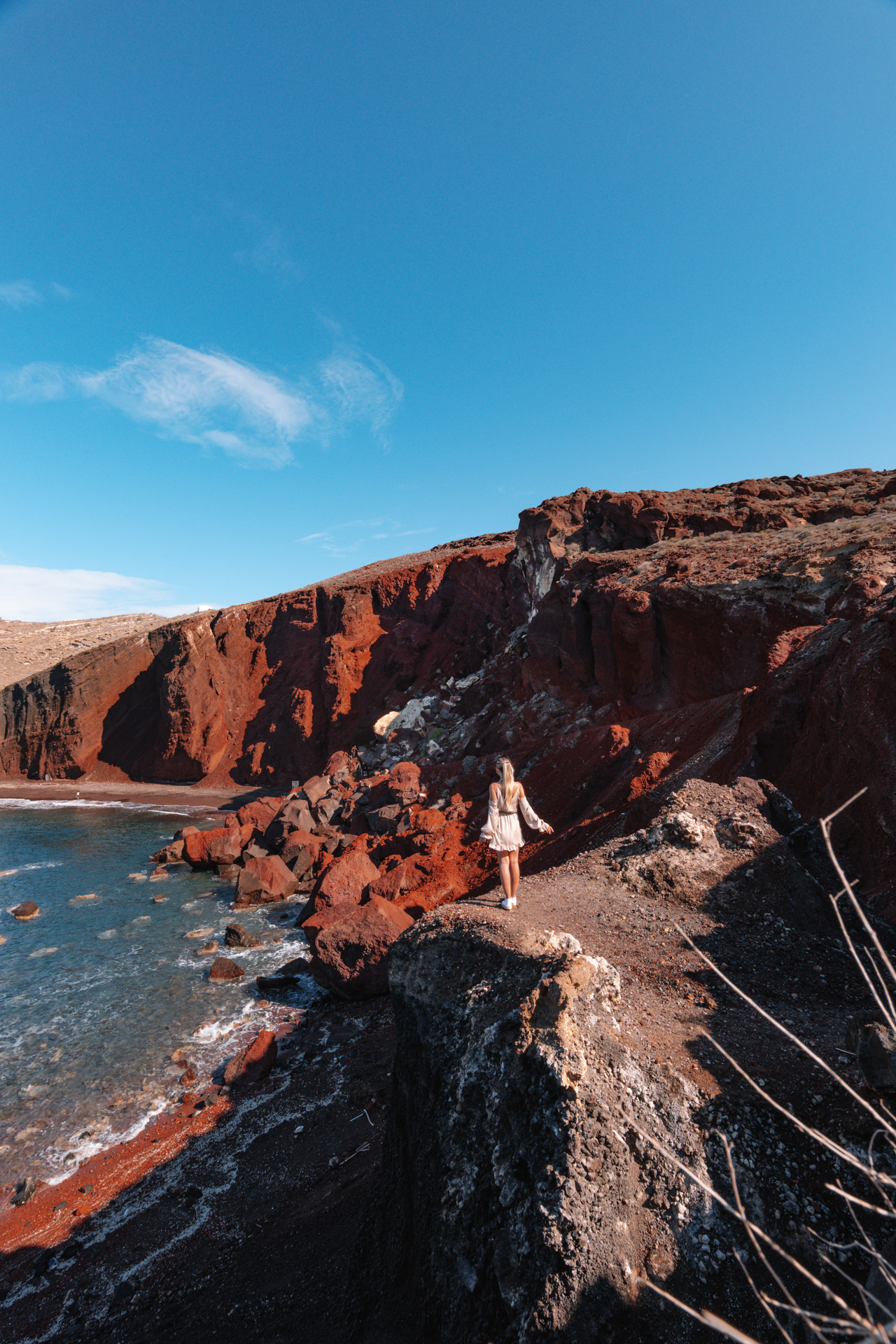 Santorini Red Beach viewpoint with volcanic cliffs and woman walking along the coast