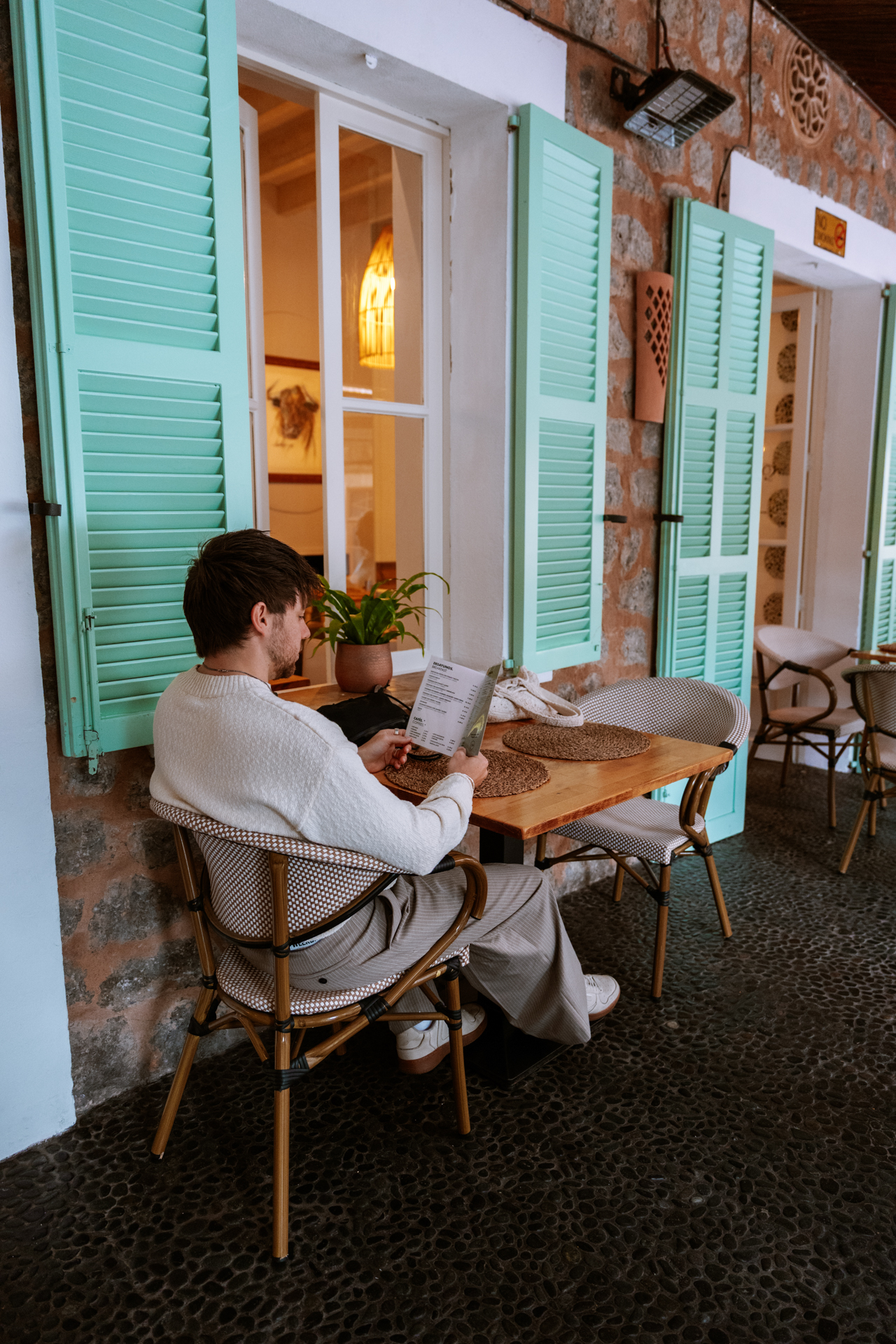 Cozy café terrace with mint green shutters and rustic Mediterranean design in Deià village, Mallorca, Spain