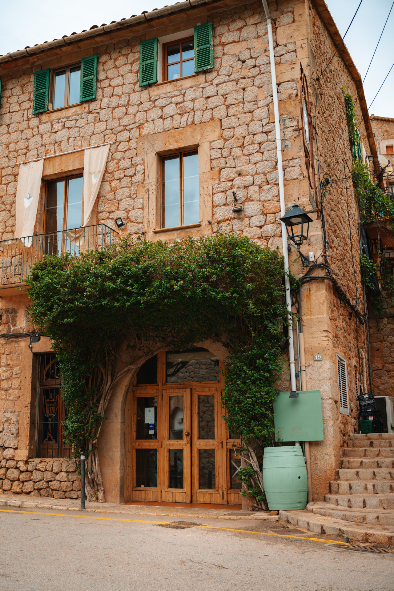 Traditional stone building with wooden doors and green shutters in Deià village, Mallorca, Spain