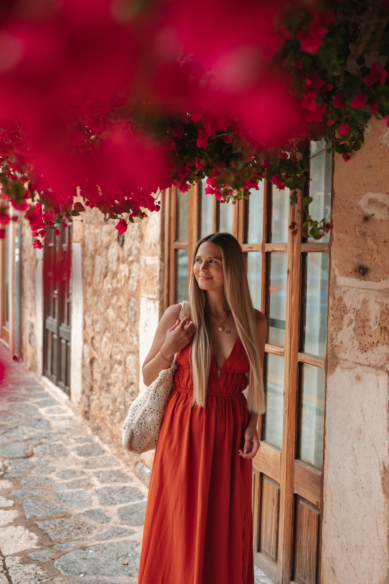 Woman in a red dress beneath bougainvillea flowers in Deià, Mallorca, Spain