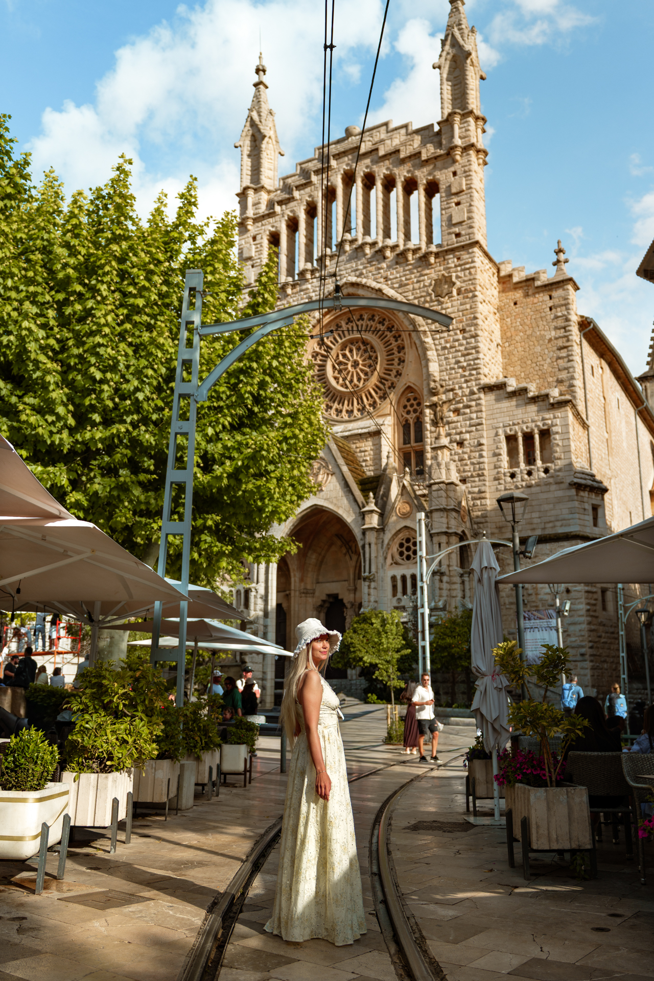 Woman standing by the famous tram tracks in front of Sant Bartomeu Church in Sóller, Mallorca.