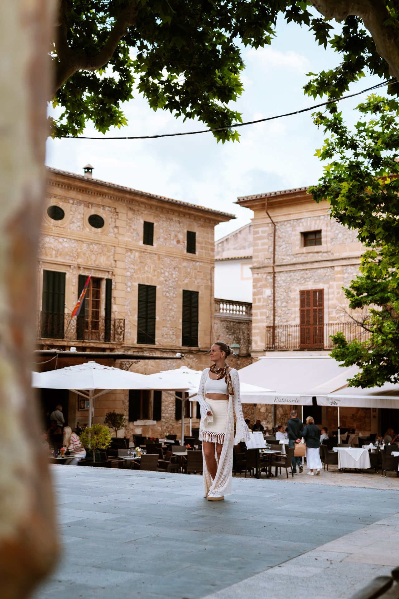 Woman walking through Plaça Major in Pollença old town, Mallorca