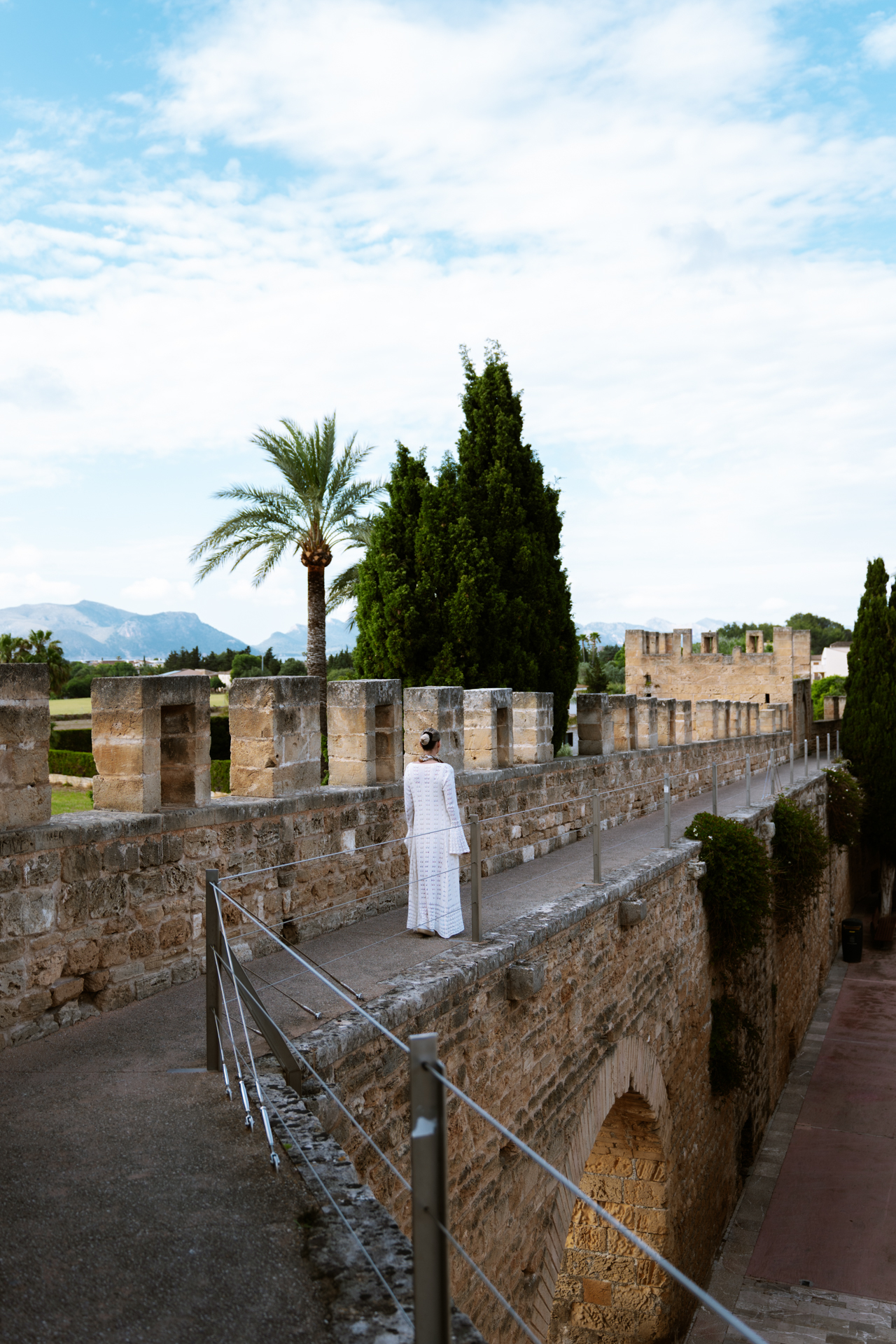 Woman walking along the medieval walls of Alcúdia Old Town in Mallorca.
