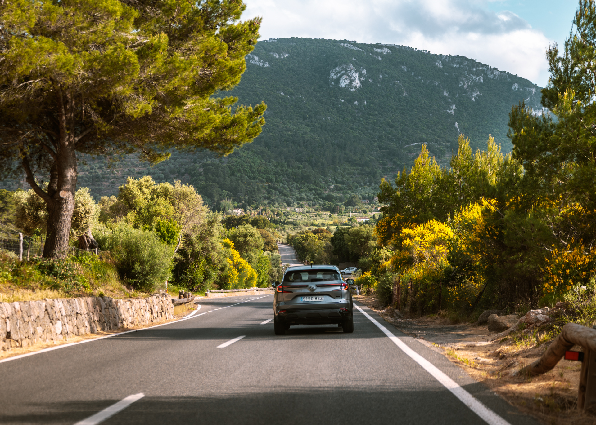 Car driving on scenic mountain road surrounded by pine trees on Mallorca
