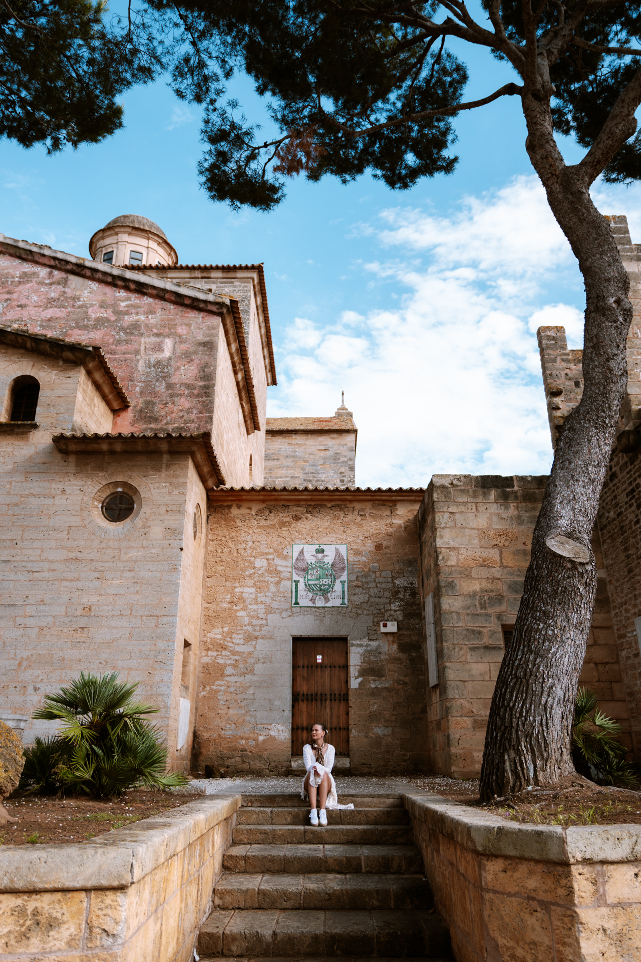 Woman sitting beside Sant Jaume Church and the medieval walls of Alcúdia Old Town, Mallorca.