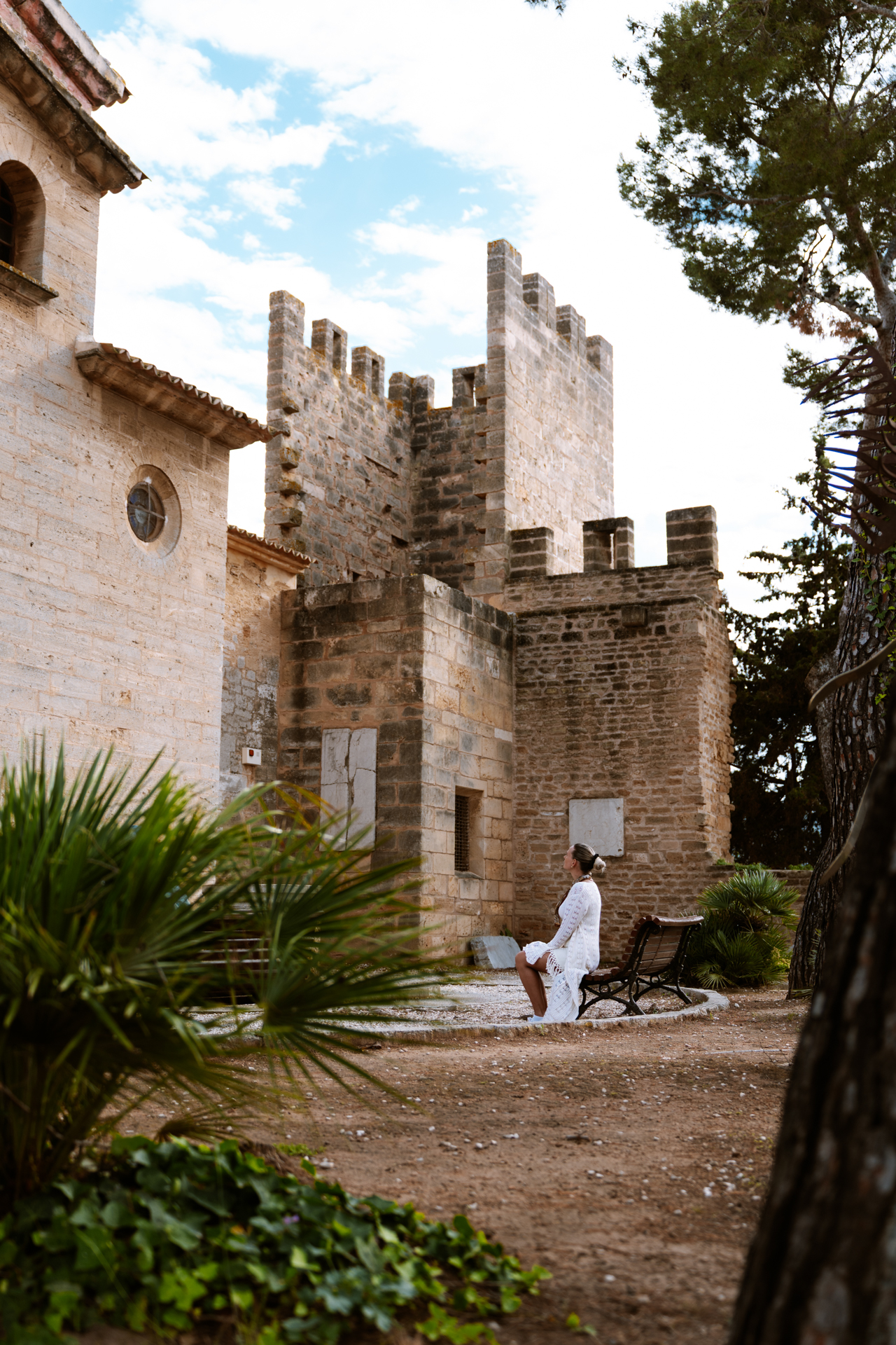 Woman sitting beside Sant Jaume Church and the medieval walls of Alcúdia Old Town, Mallorca.